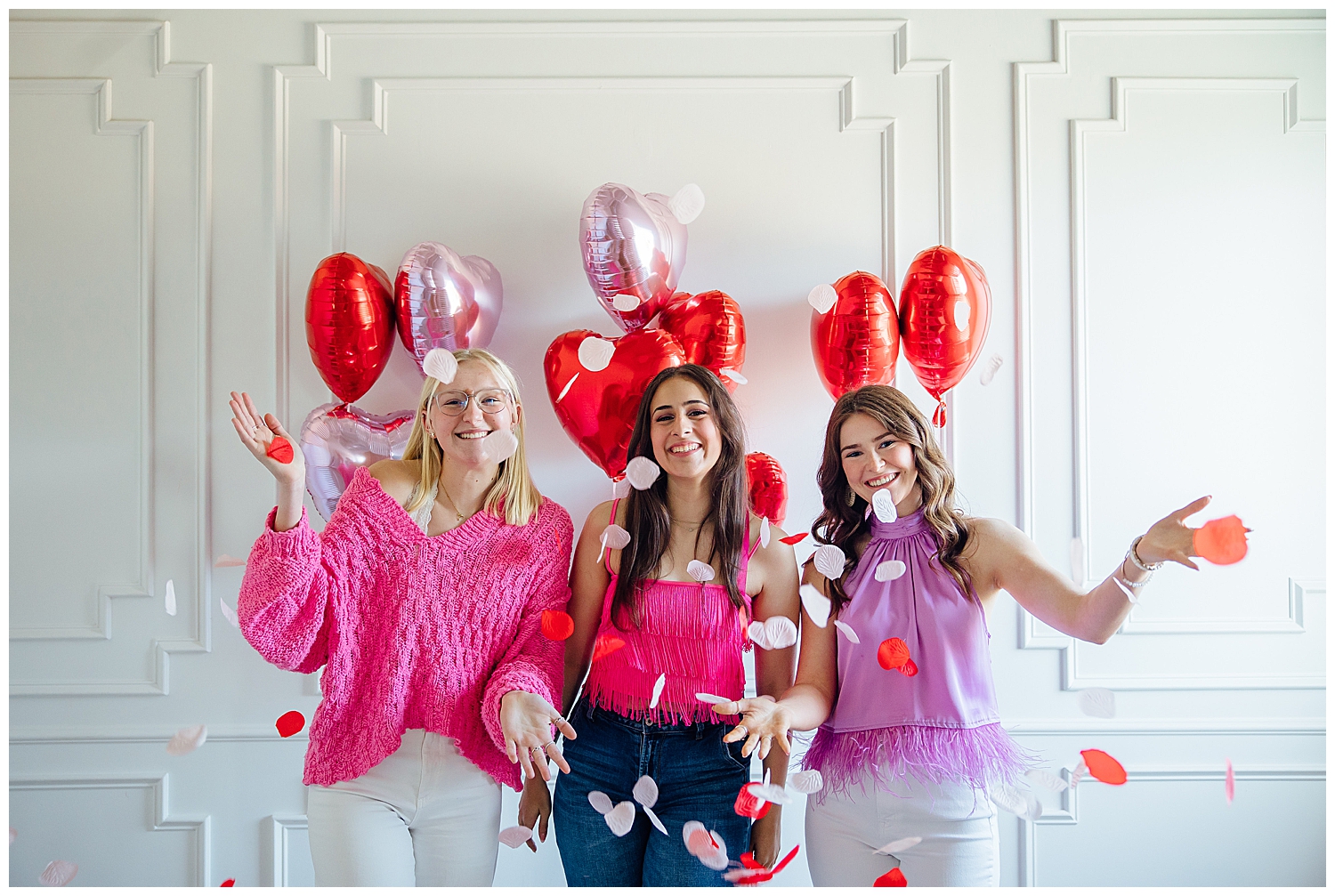 three girls in white and pink tossing rose petals for Valentine's Day Senior Photoshoot