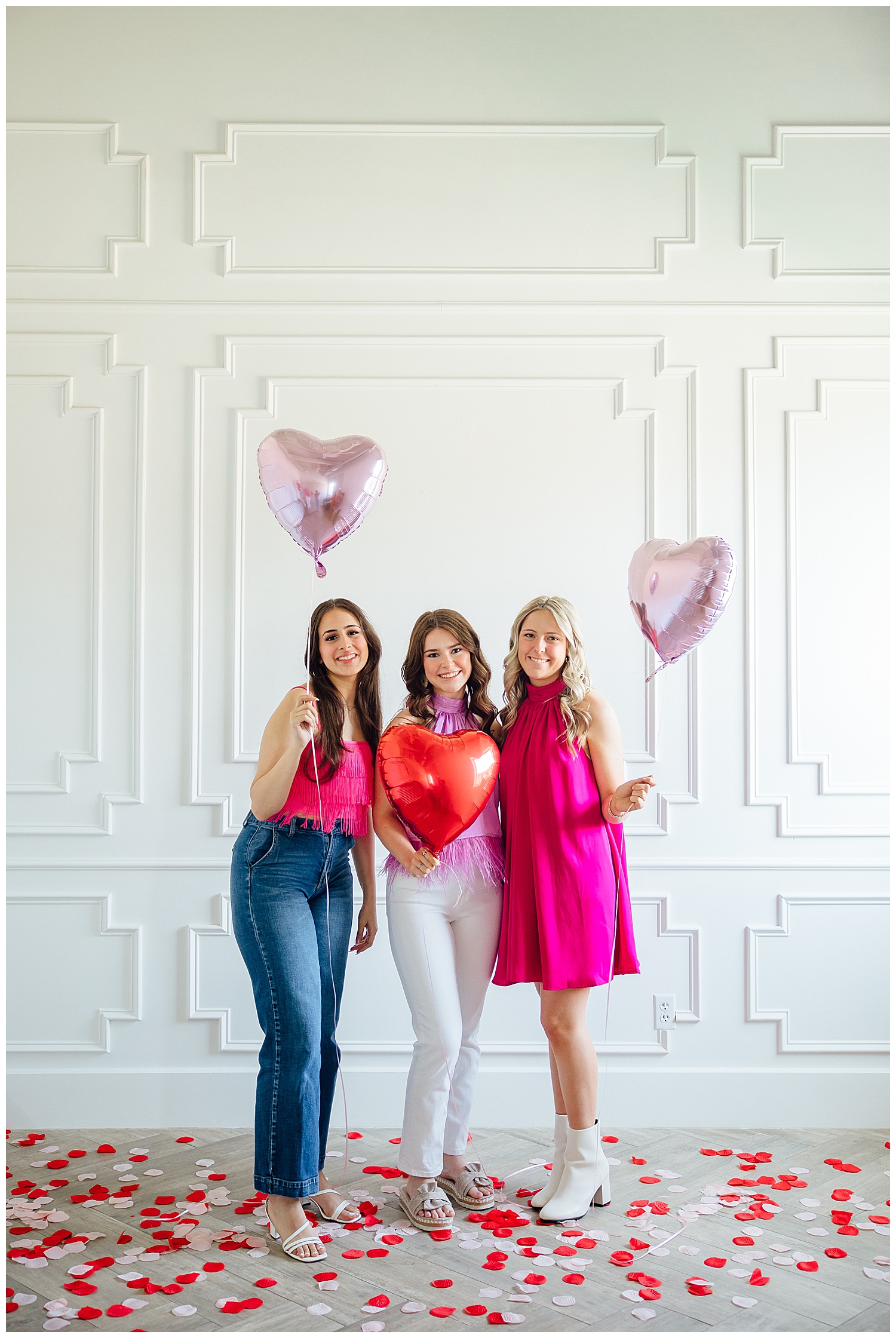 three girls in hot pink standing and holding heart balloons