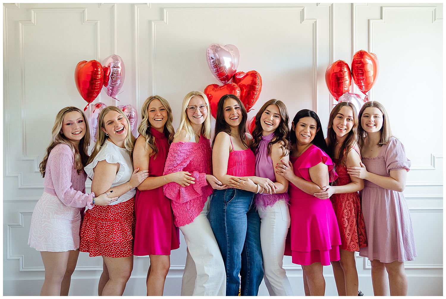 Houston senior spokesmodel team of girl in red, white and pink smiling and standing in front of white wall with heart balloons