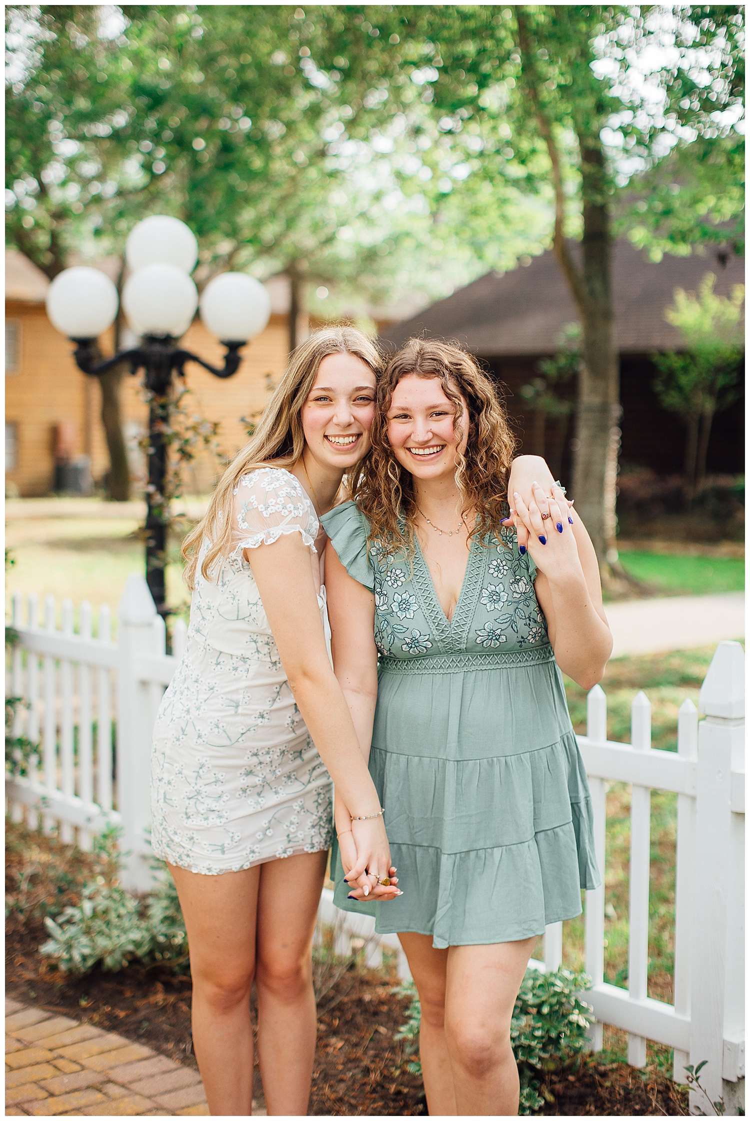 two girls holding hands outdoors in dressing for best friends senior pictures at Cy Hope near Houston