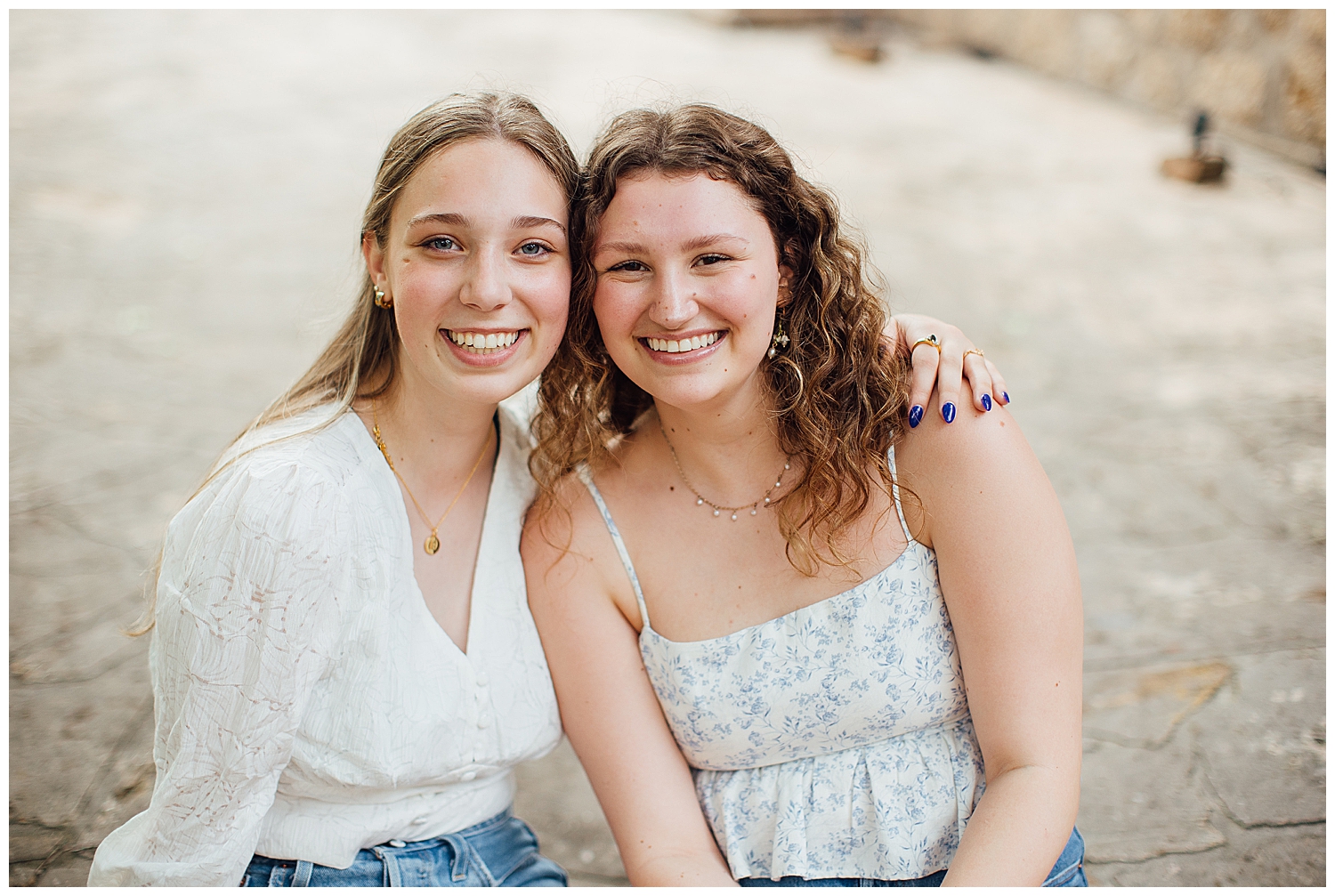 two high school senior girls sitting and smiling at camera for best friends senior pictures