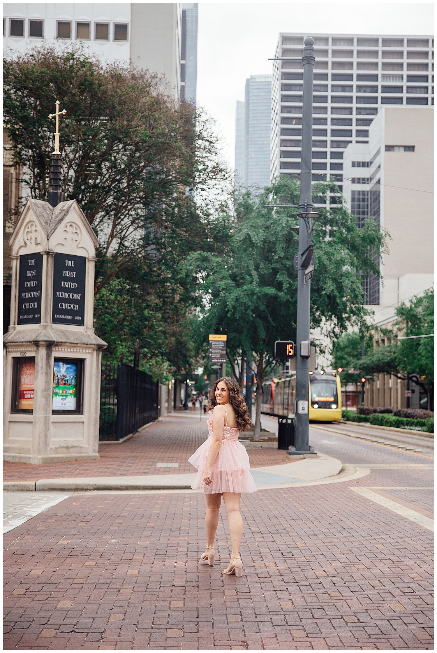 senior girl in pink fluffy dress crossing Main Street downtown Houston