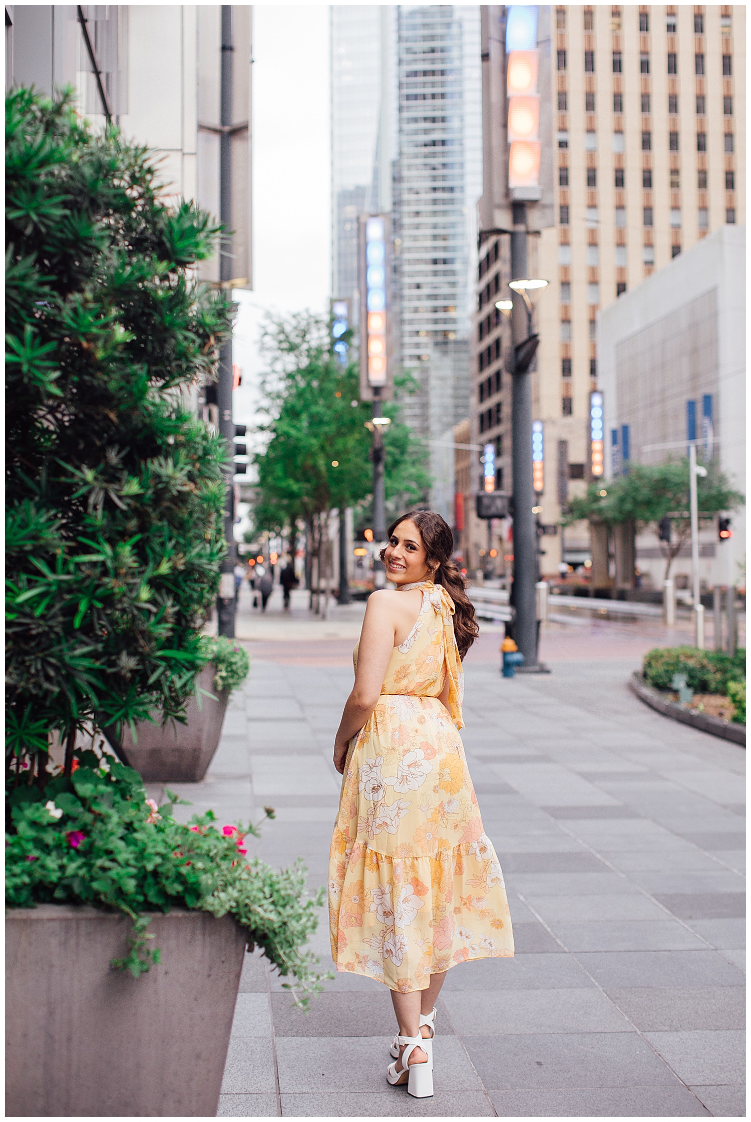 girl in yellow floral dress crossing Main Street for downtown Houston senior pictures
