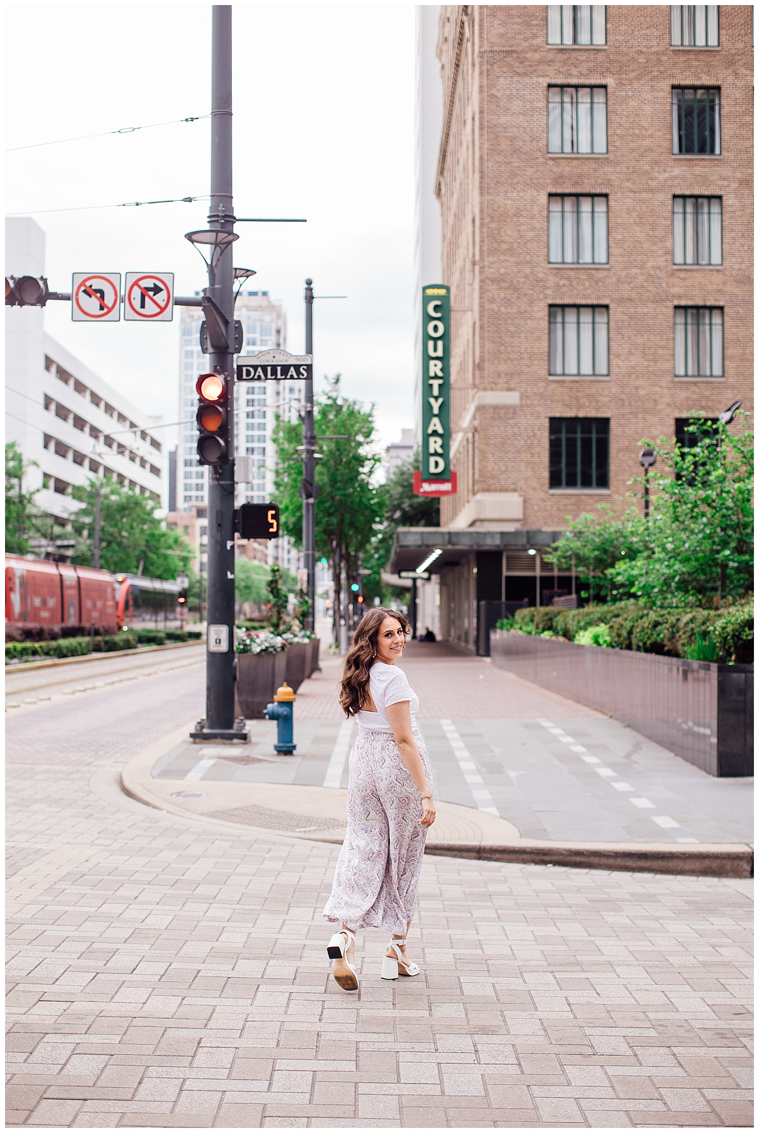 girl in white pants and white shirt crossing the street in downtown Houston senior pictures