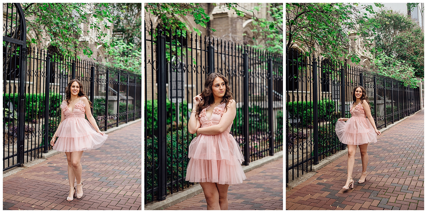 girl in pink fluffy dress standing in front of rod iron fence