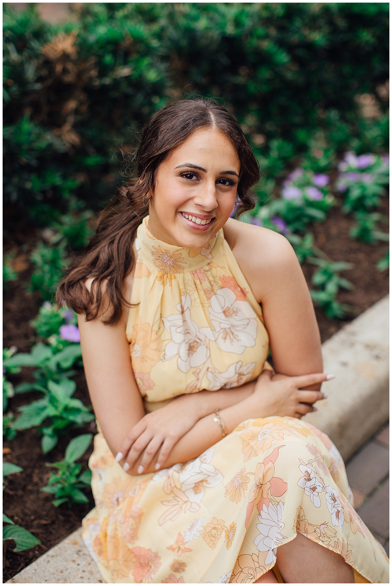 girl sitting in front of flowers smiling for downtown Houston senior pictures
