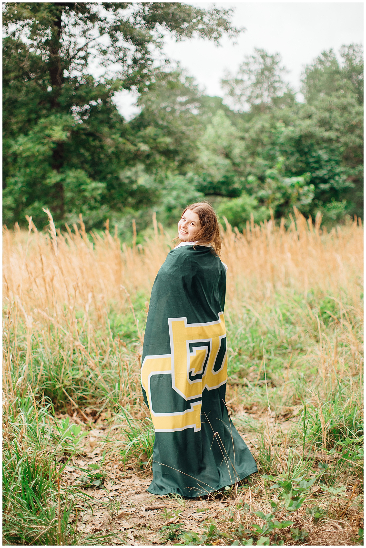 high school senior girl wrapped in Baylor university banner standing in a field