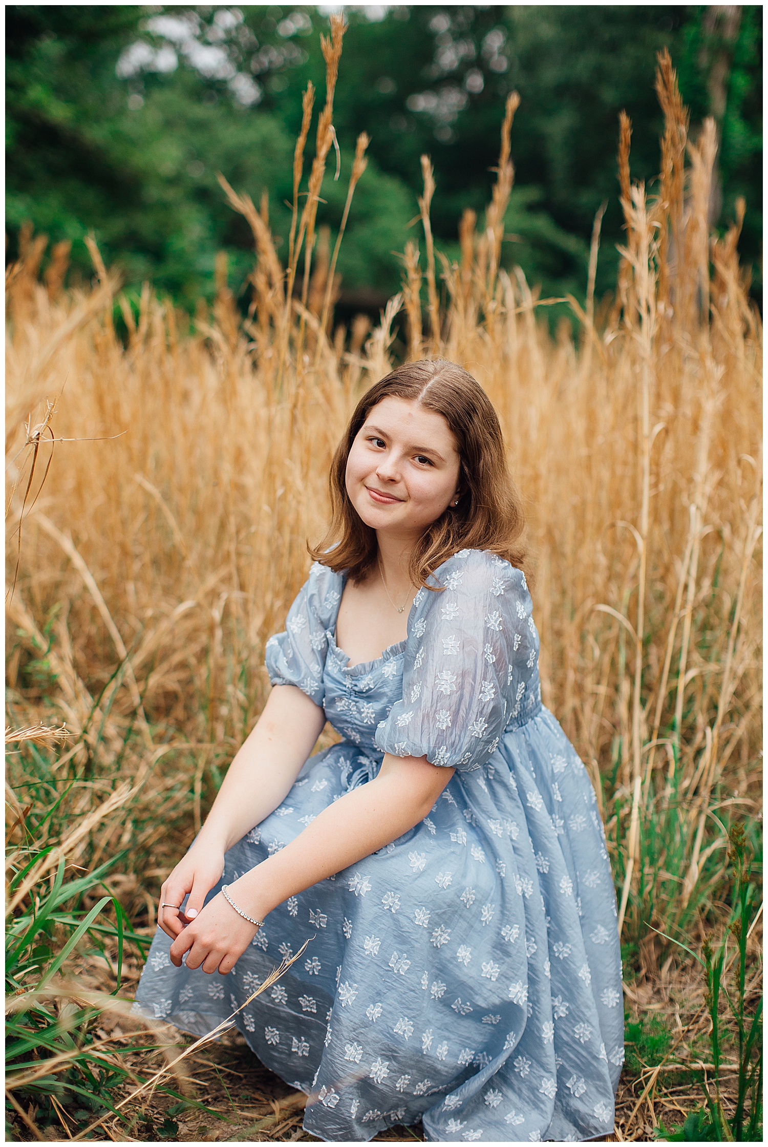 girl in blue dress sitting in a field at Houston arboretum outdoor spring senior photos