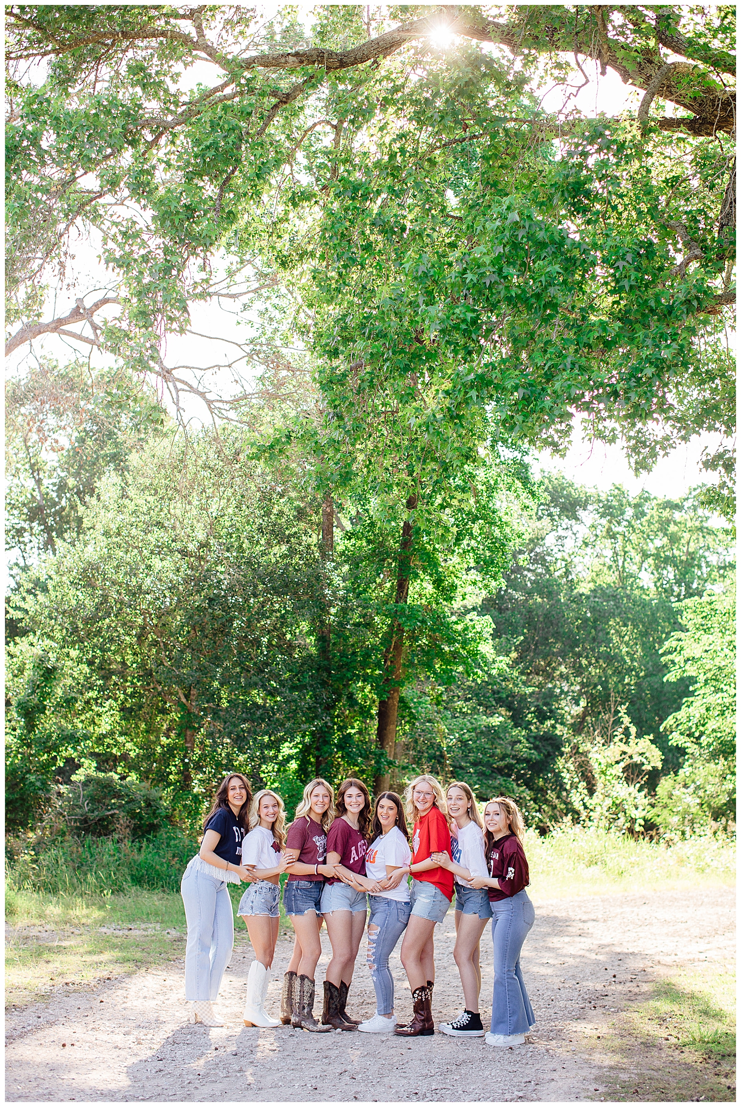 college shirt senior photos with girls holding hands under a tree