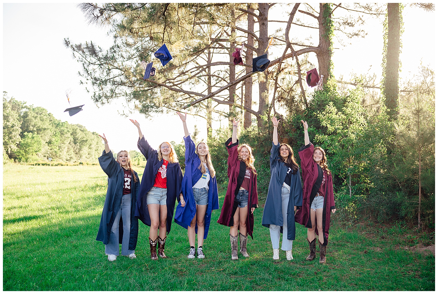 high school senior girls throwing cap and gown outside at Cy-Hope