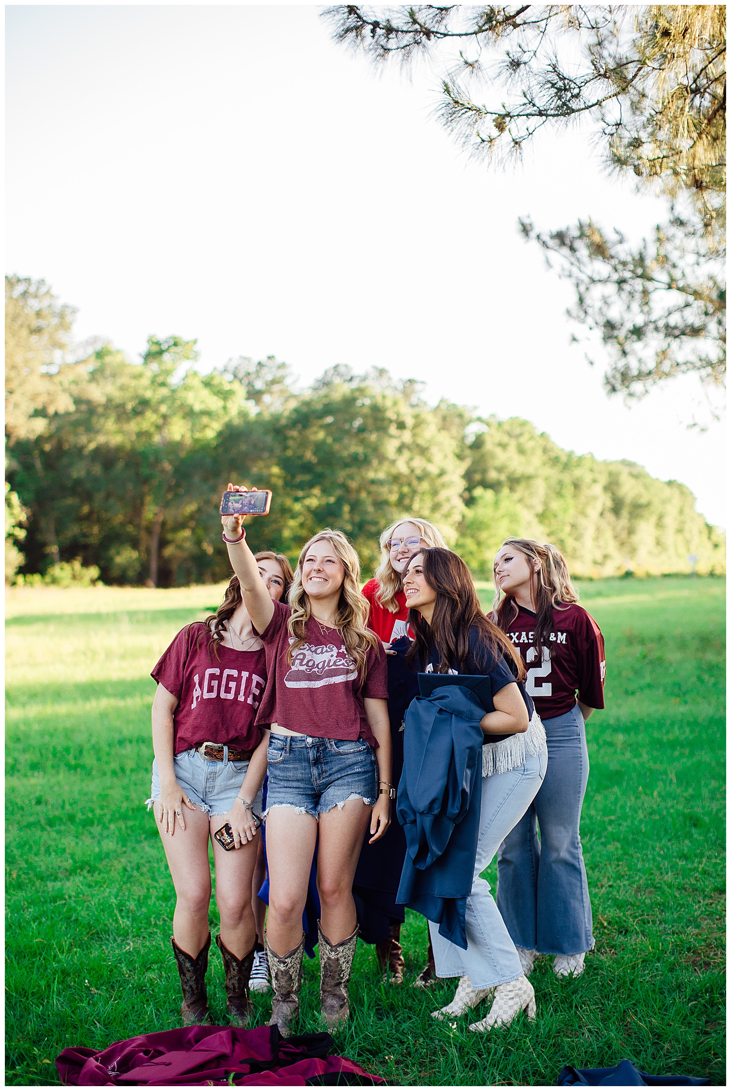high school senior girls taking selfie in a field for college shirt senior photos