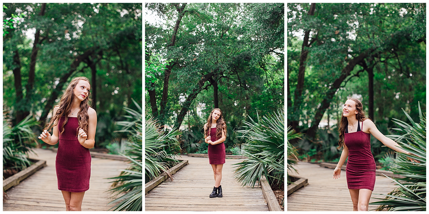 girl in burgundy dress and black boots standing on pathway at Hermann park for outdoor senior photos Houston