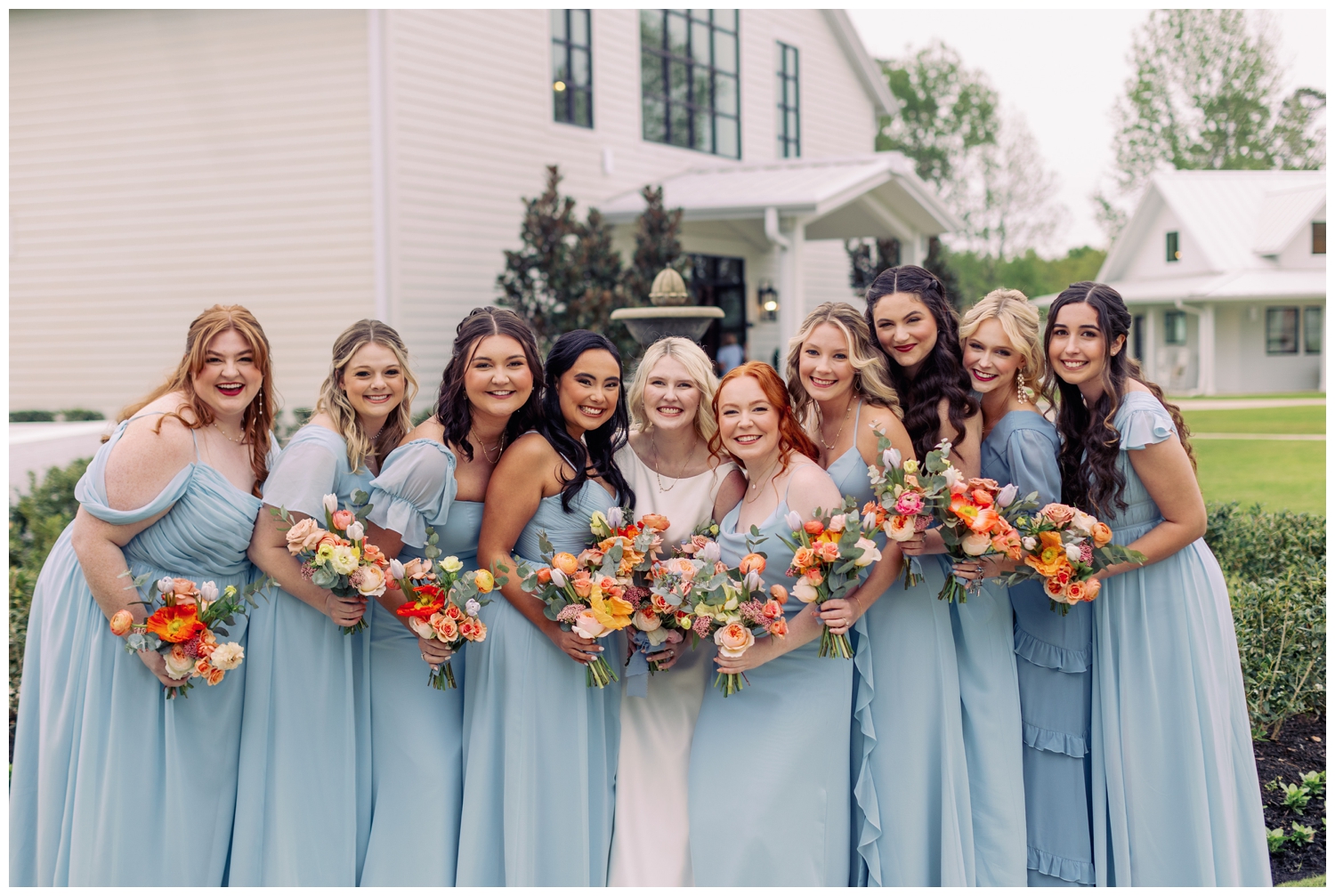 bridesmaids in sky blue dresses with bride outside Boxwood Manor wedding venue