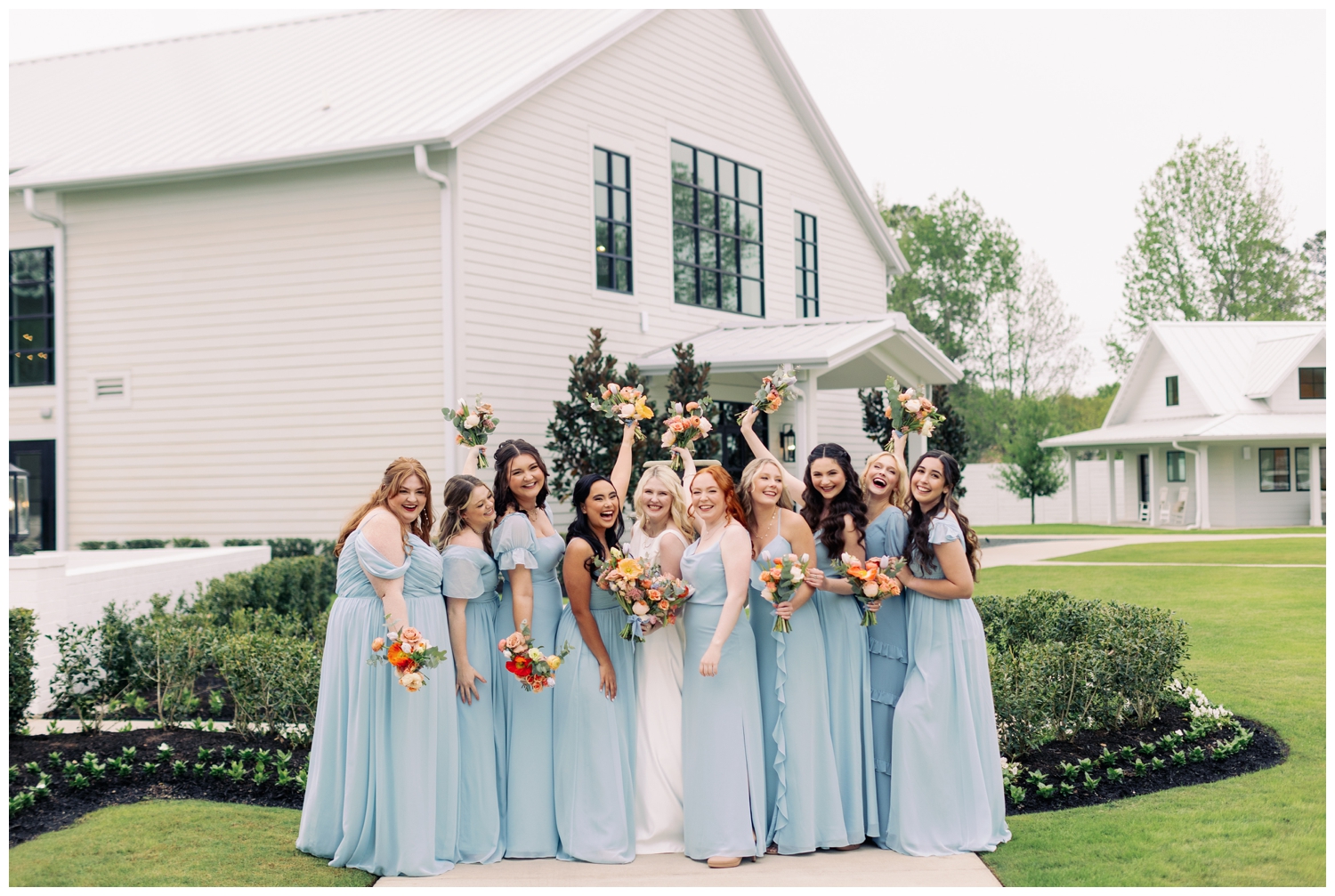 bride with bridesmaids with hands in air standing outside in Tomball Texas