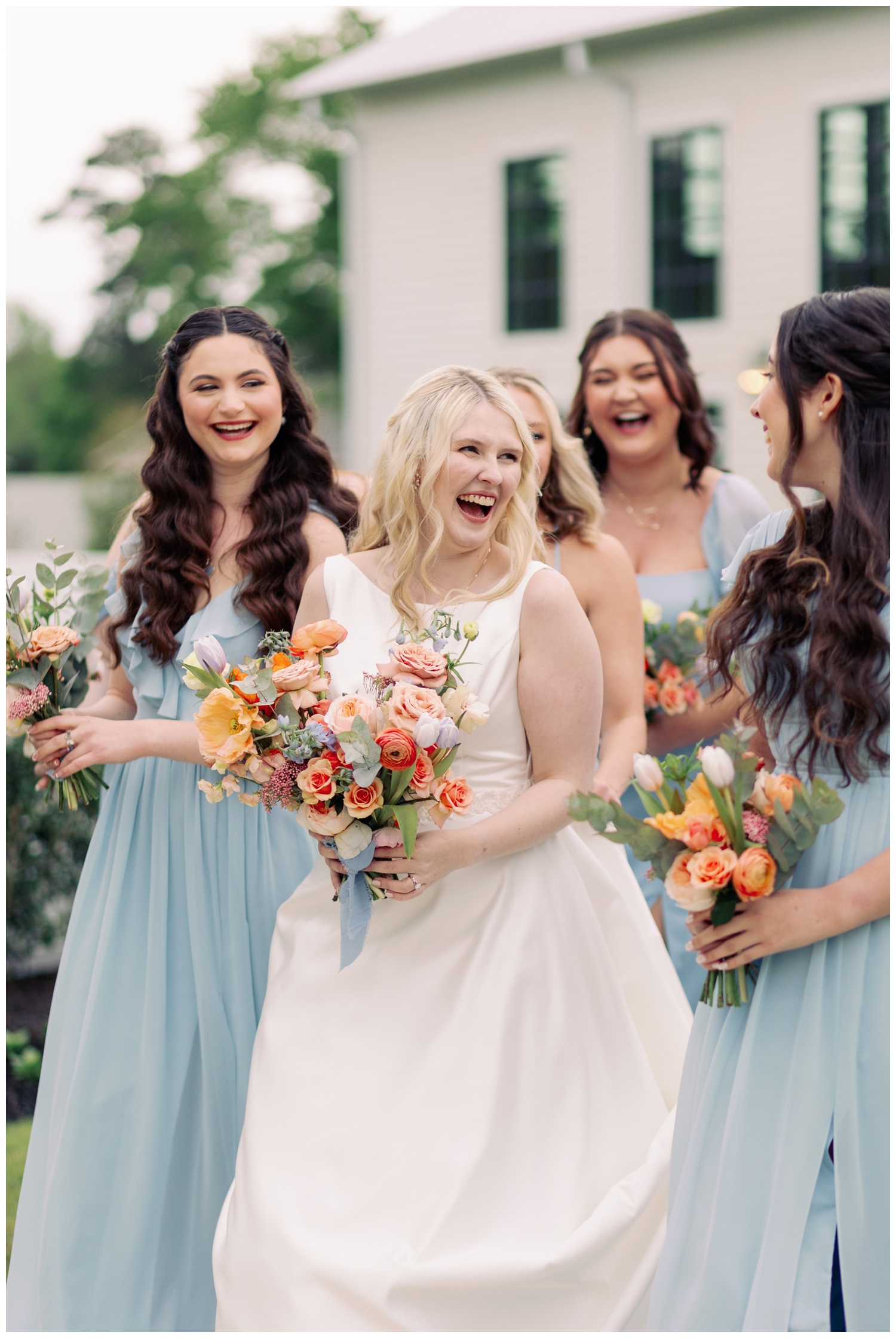 bride laughing and walking outside boxwood manor wedding venue with bridesmaids