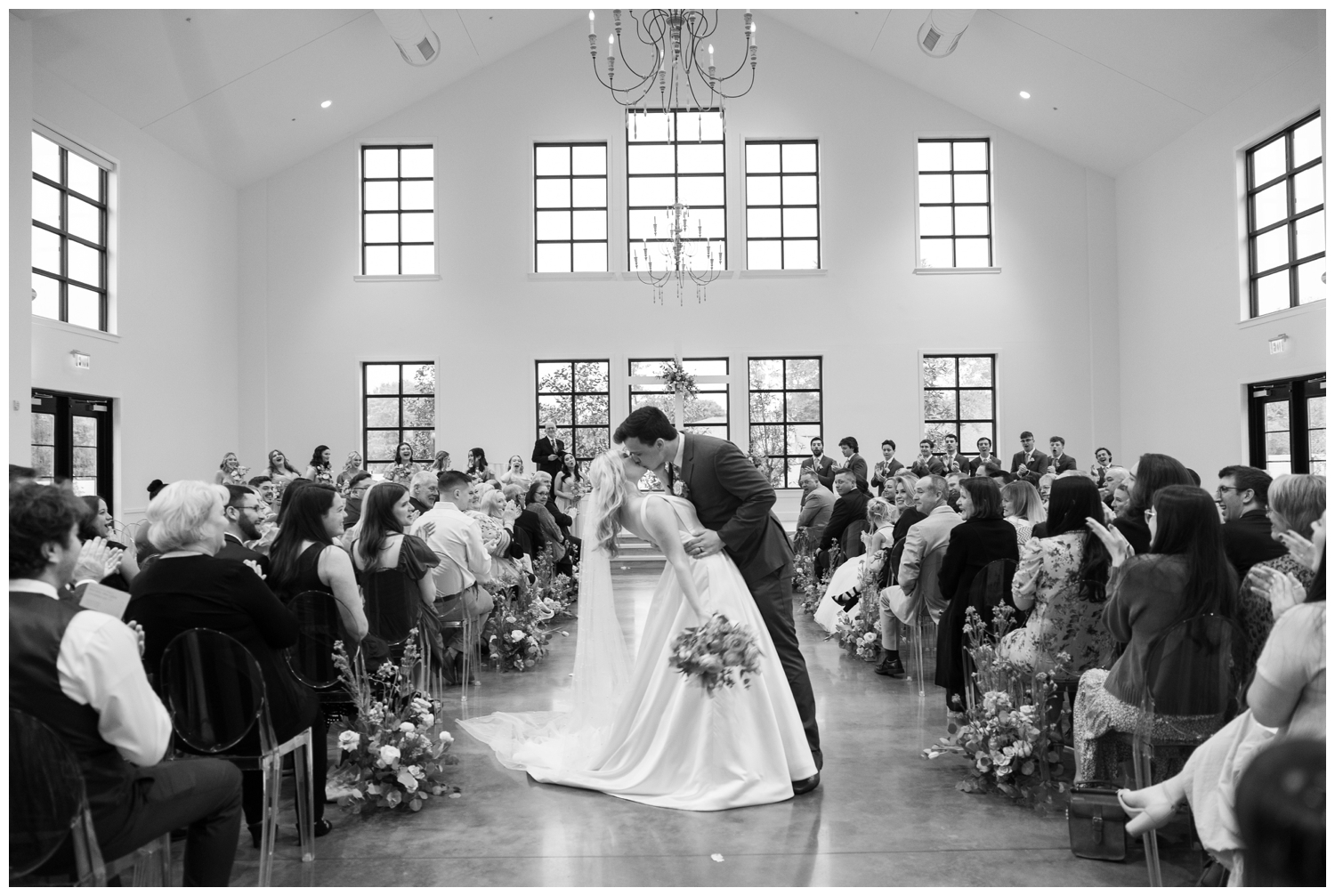 black and white image of bride and groom kissing during ceremony exit Boxwood Manor