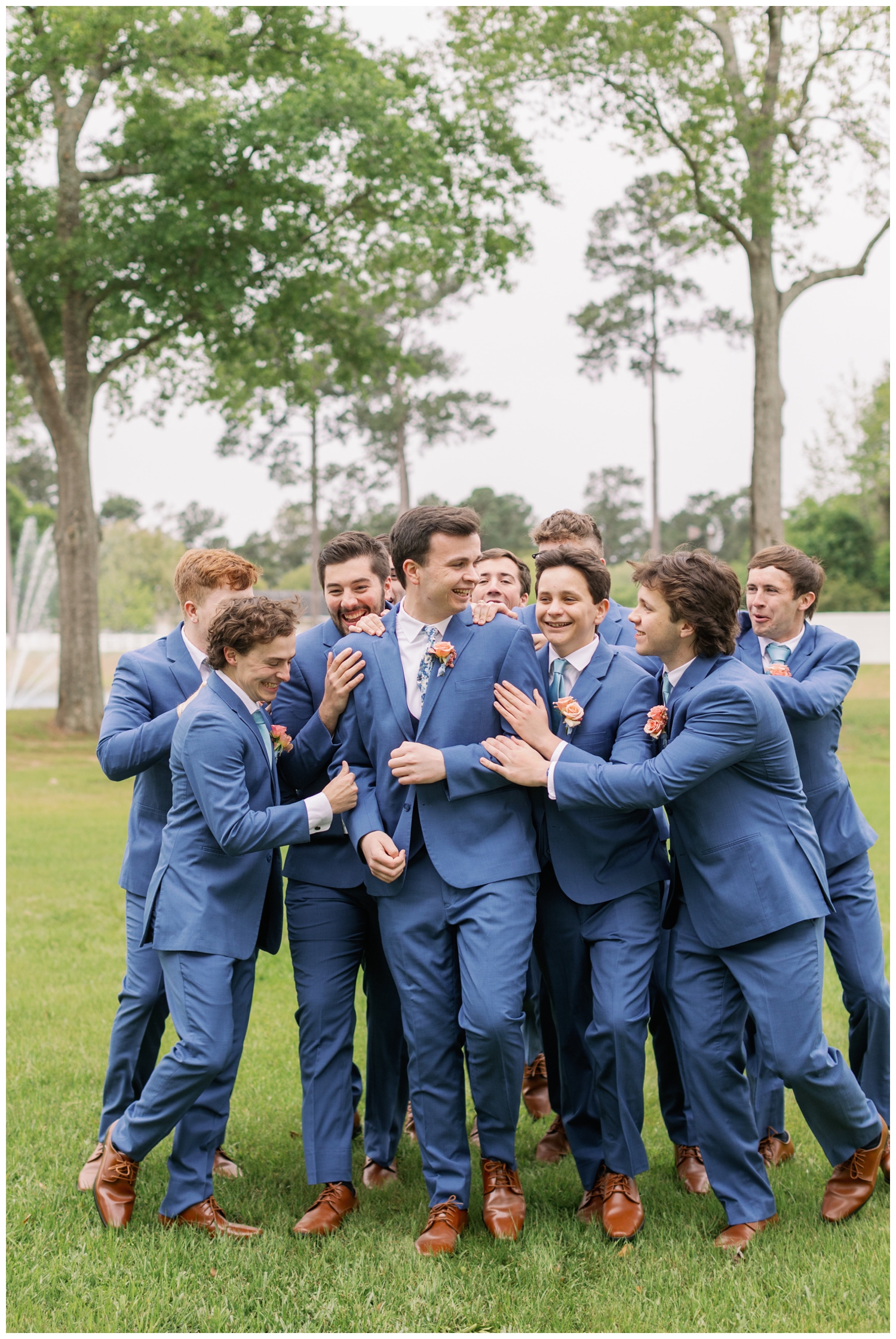 groom surrounded by groomsmen in a huddle on grass at Boxwood Manor Wedding venue