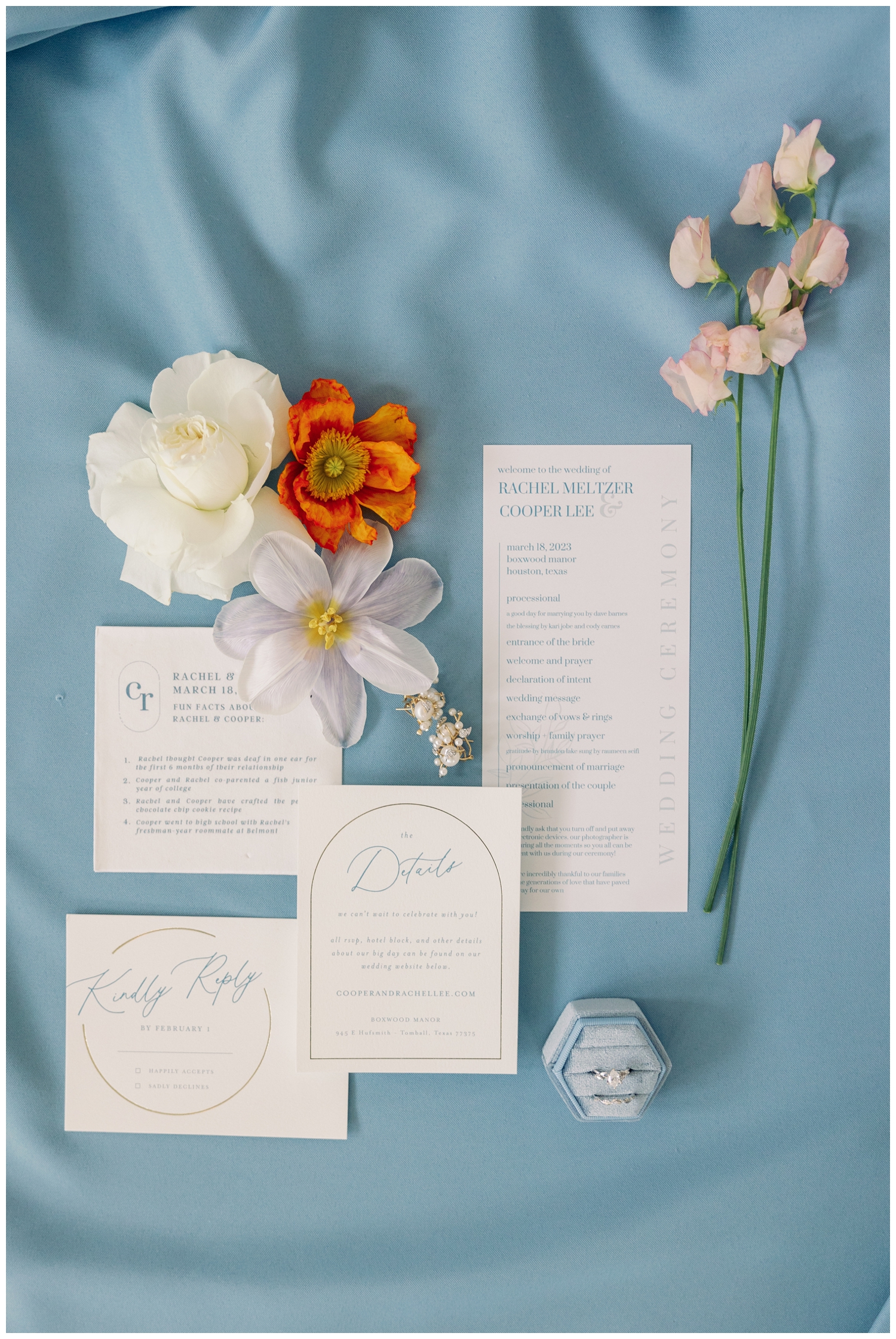 all white invitation suite with florals on light blue styling mat