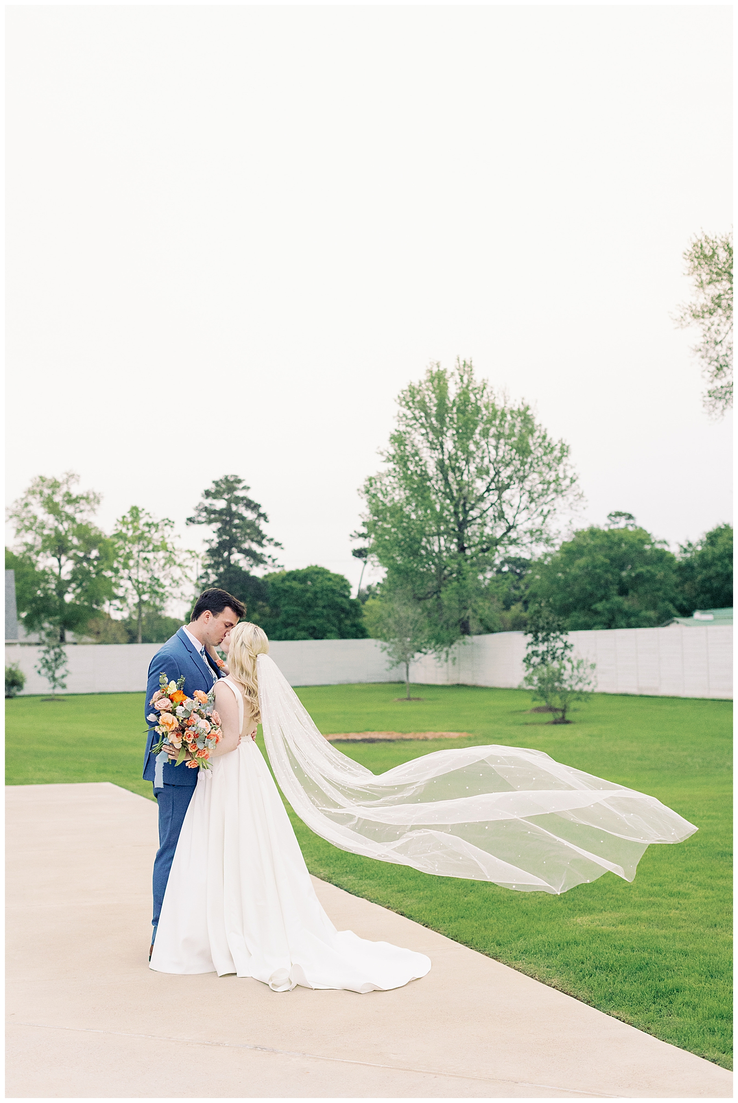 bride and groom nuzzling with long veil swoop on lawn at Boxwood Manor wedding