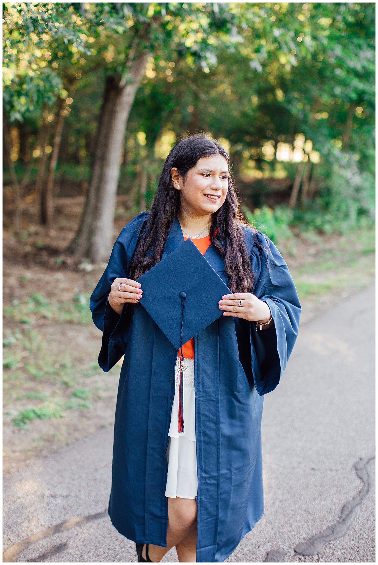 senior girl holding navy cap and gown outdoors Houston, Texas