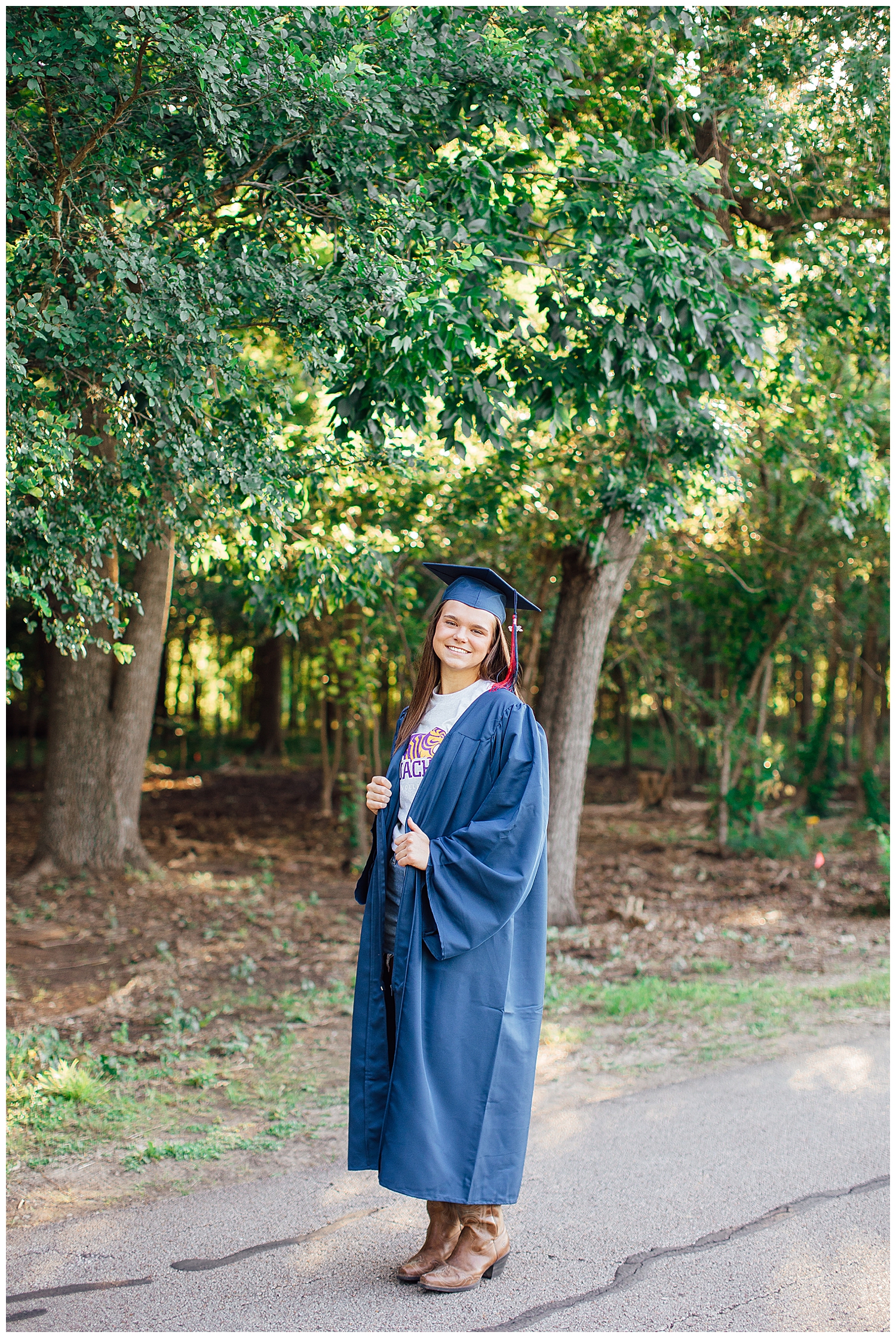 senior girl posing in cap and gown under trees