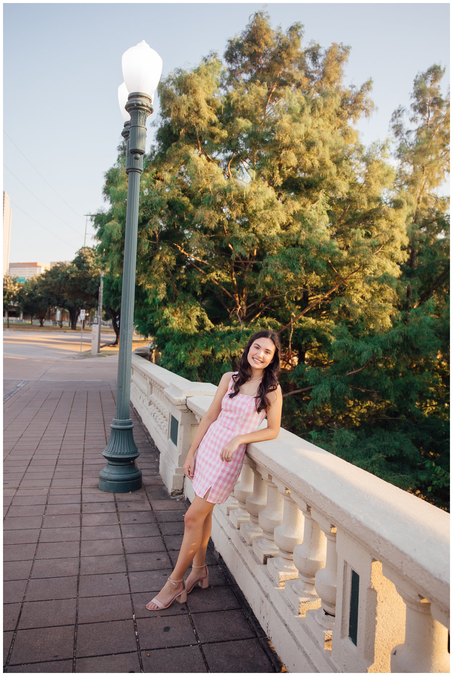 high school senior girl leaning on Sabine Street bridge in pink dress