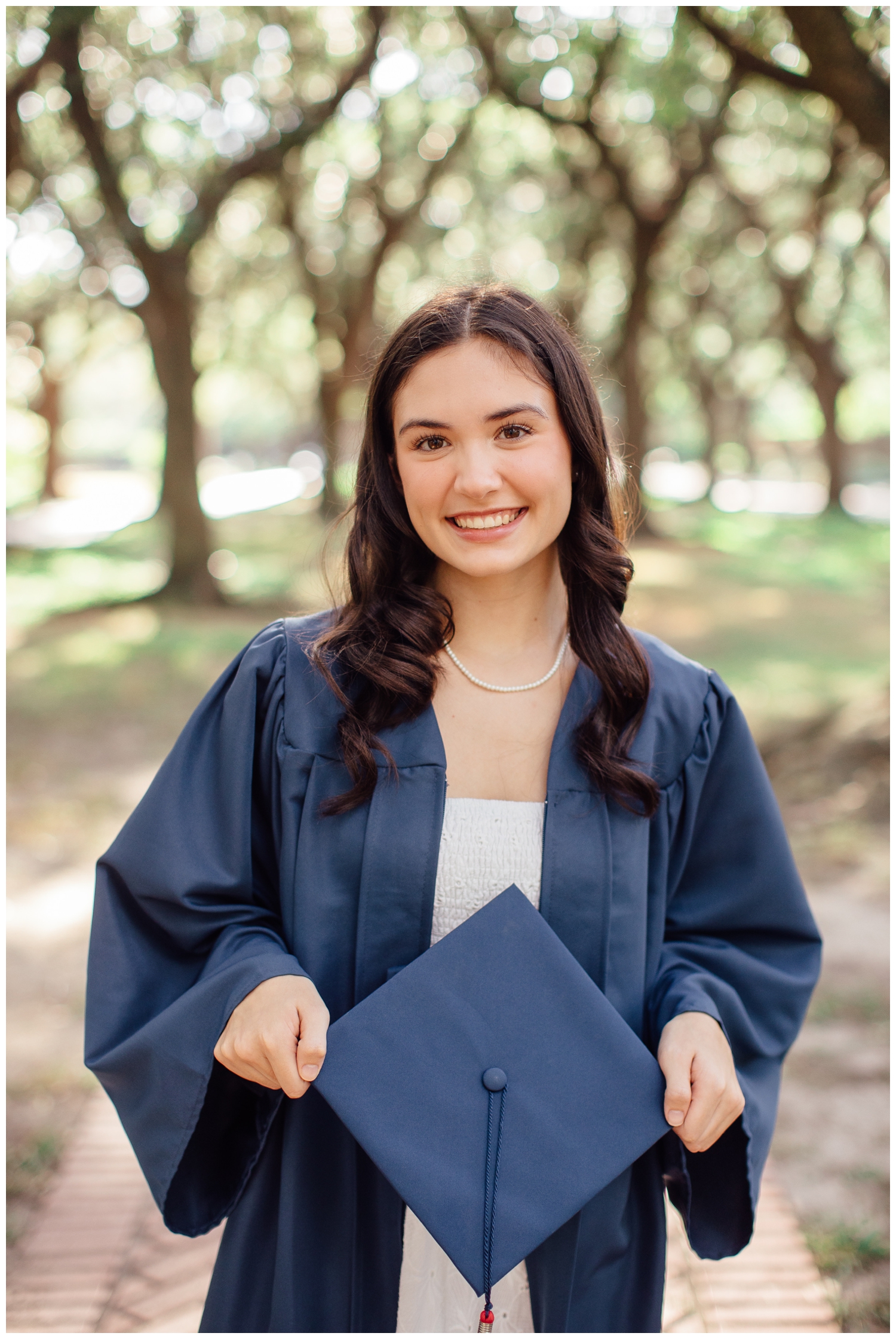 high school girl in navy cap and gown standing outside for senior photos Houston, Texas