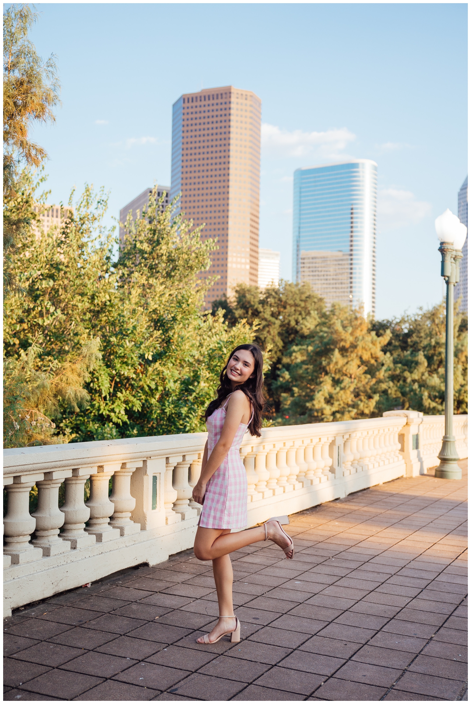 girl in pink dress standing on Sabine Street Bridge in front of Houston Syline
