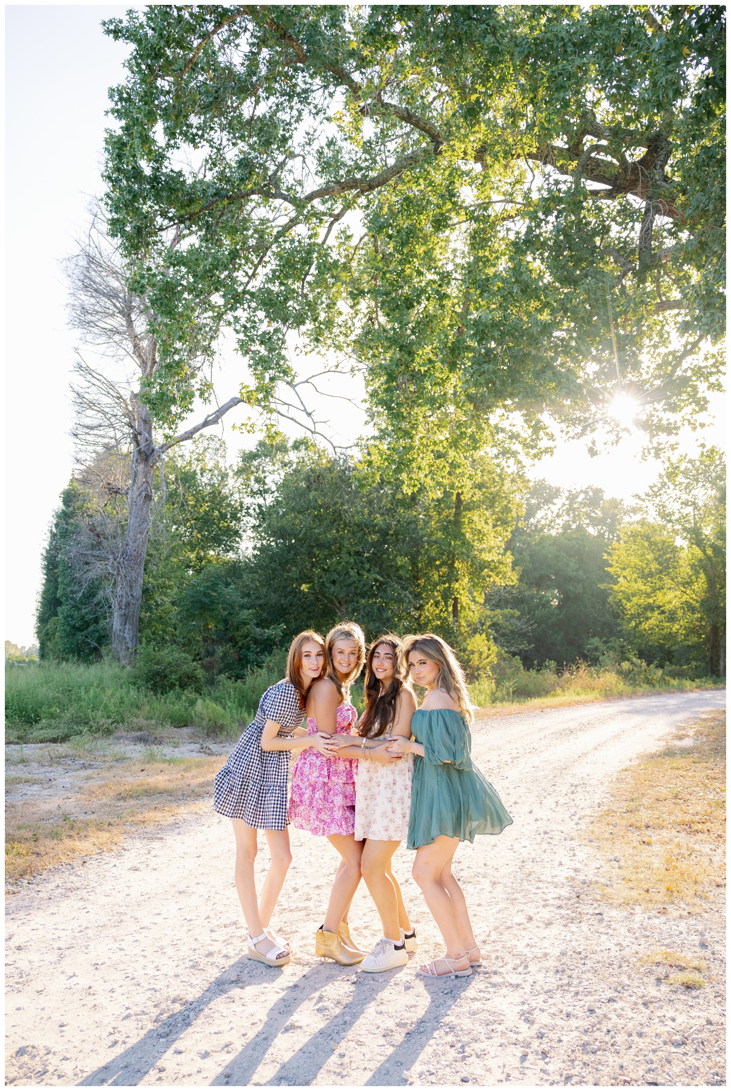 four high school senior girls in sundresses standing outside at Cy Hope