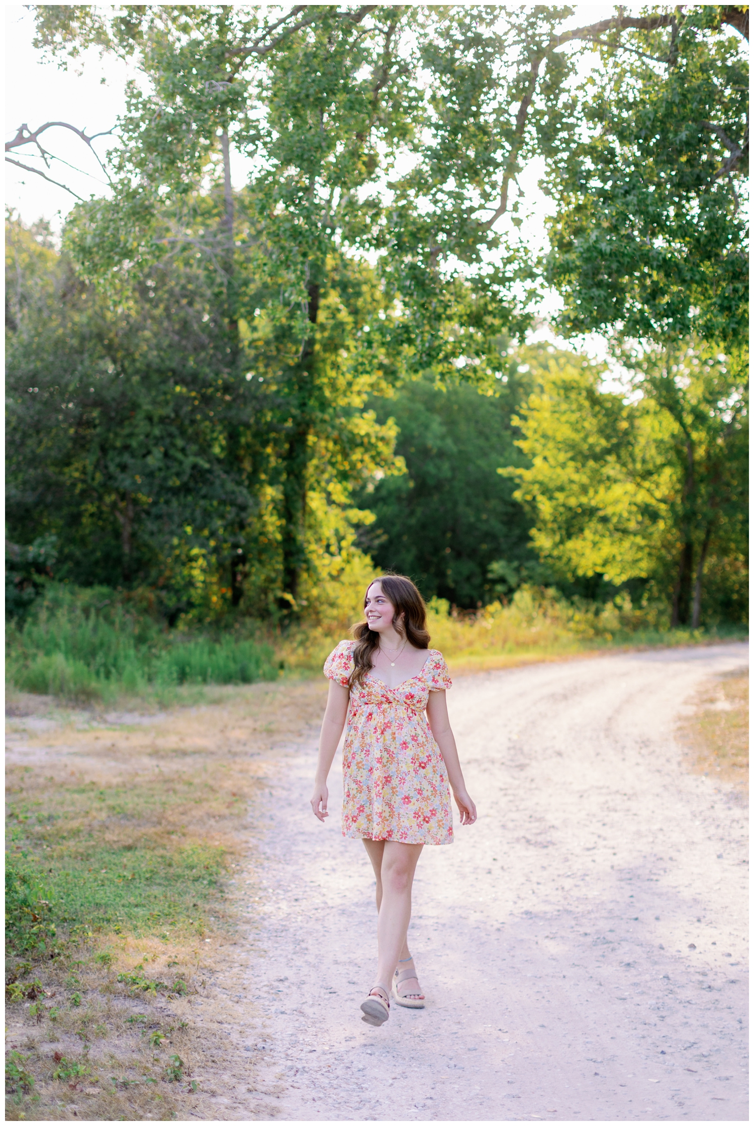 girl in floral dress walking on pathway outdoors for senior rep team Houston shoot