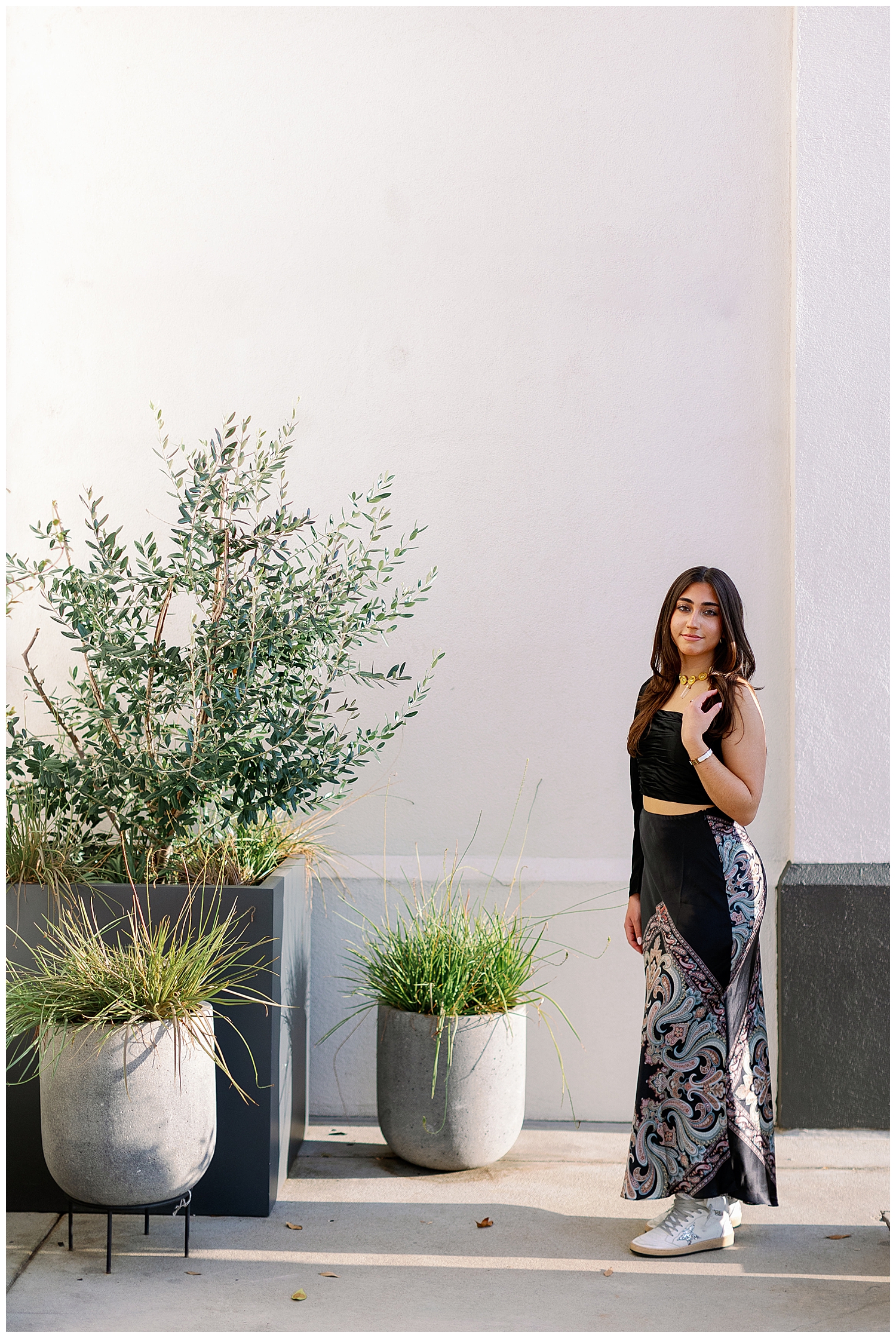 Uptown Park white wall with greenery and girl standing in front in black dress