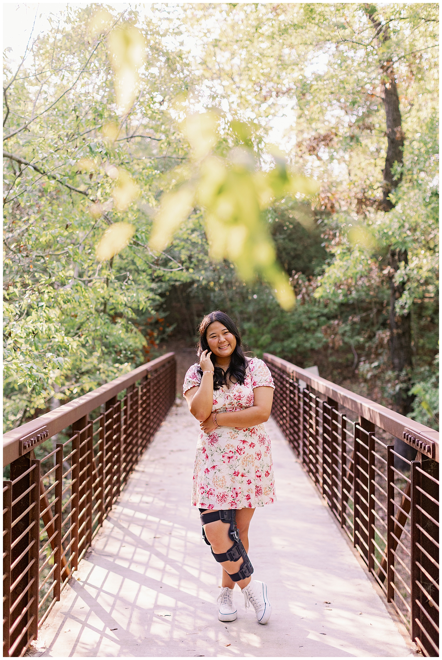 high school senior girl in floral dress standiing on a bridge in Houston, texas