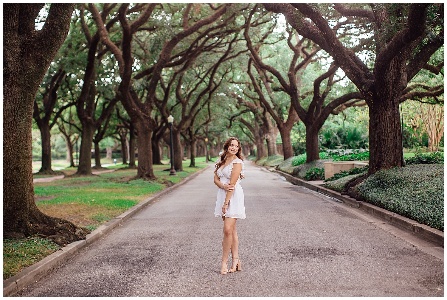 high school senior girl in white dress standing at tree line North South Blvd Houston
