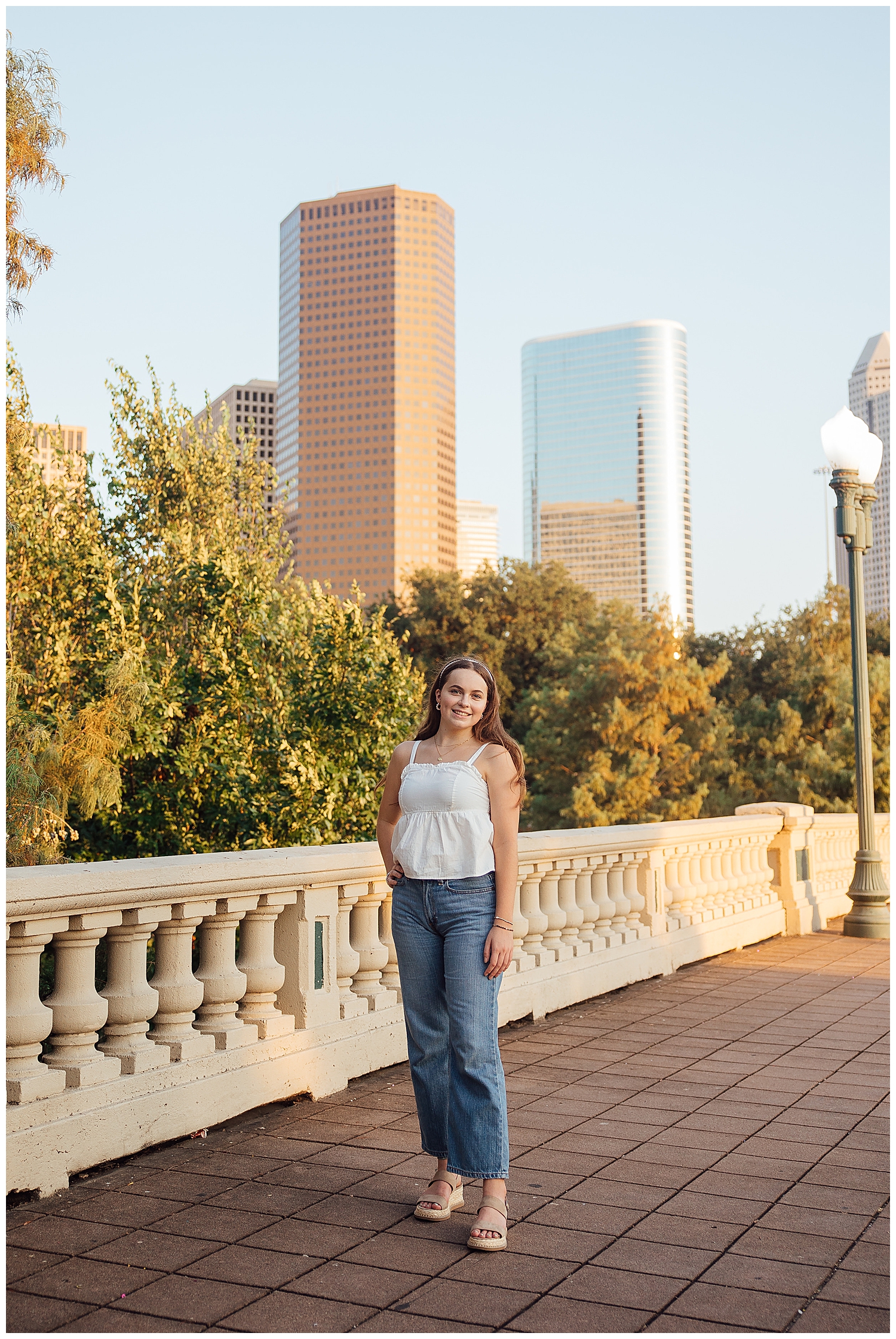 girl in jeans and white shirt standing on Sabine Street Bridge with Houston skyline