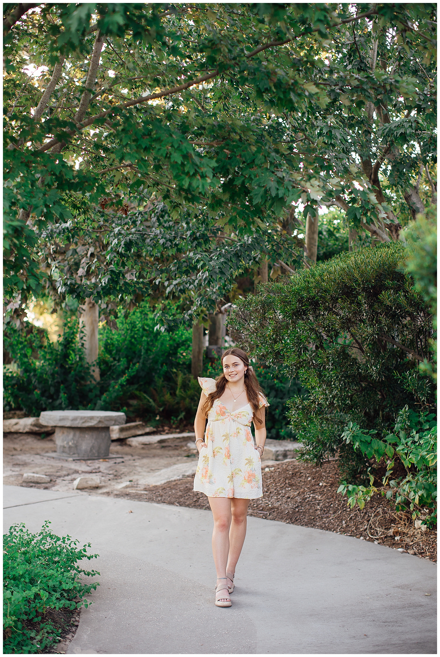 girl walking outdoors with hands on hip yellow floral dress Houston outdoor senior photos Sabine Park