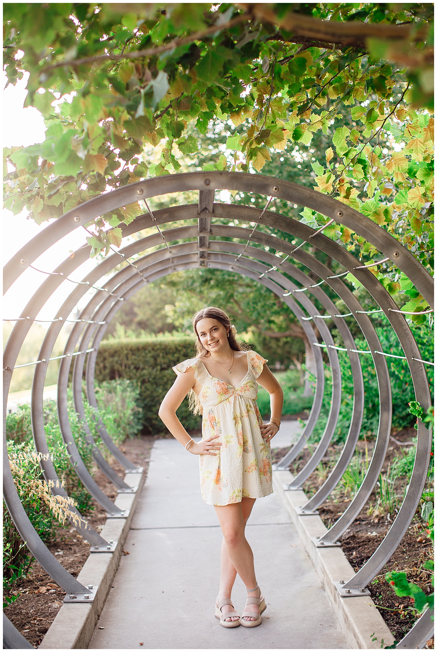 girl in floral dress standing between ring structure for Houston outdoor senior photos Lee Jamal Skatepark
