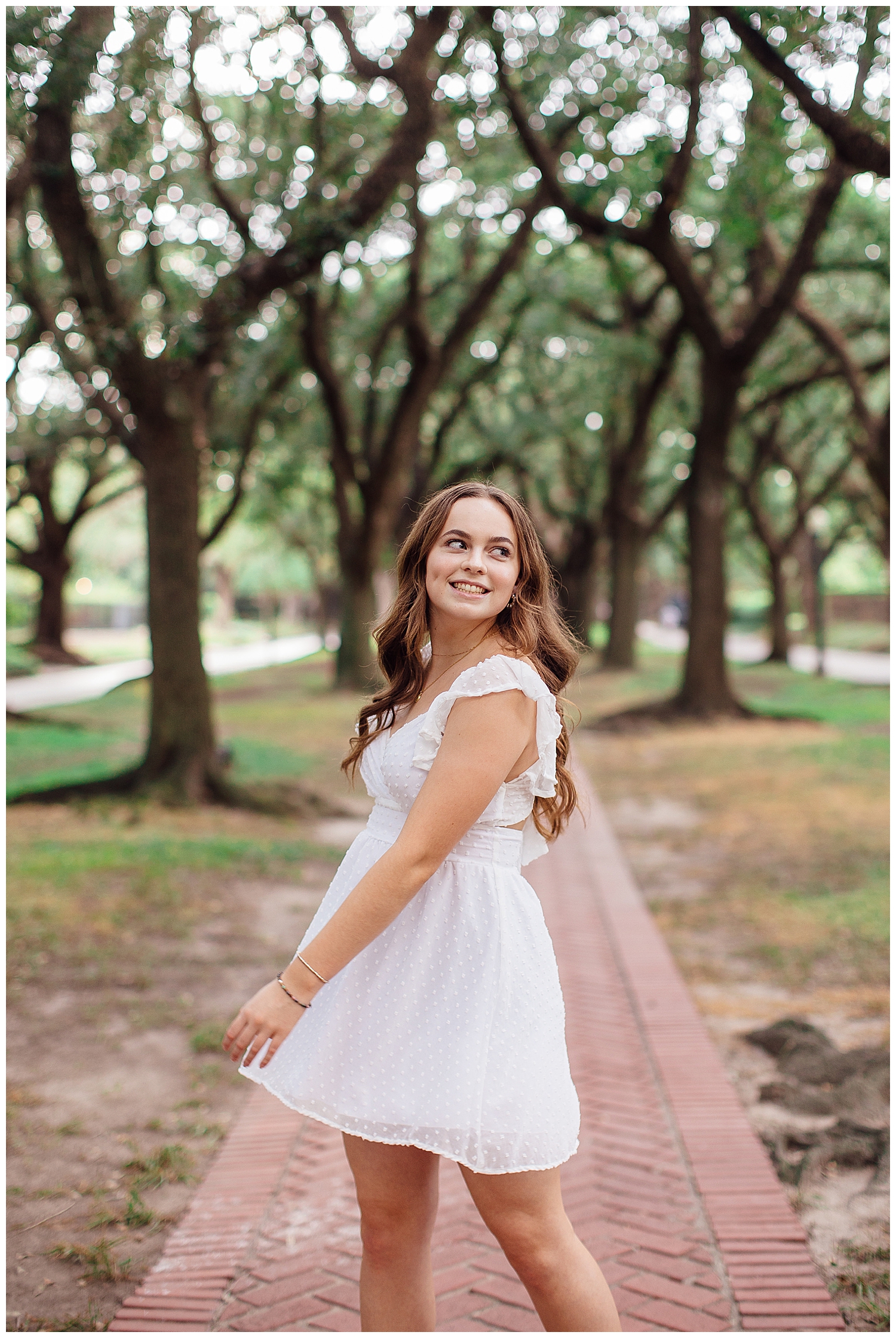 girl twirling white dress on sidewalk between trees Houston outdoor senior photos museum district