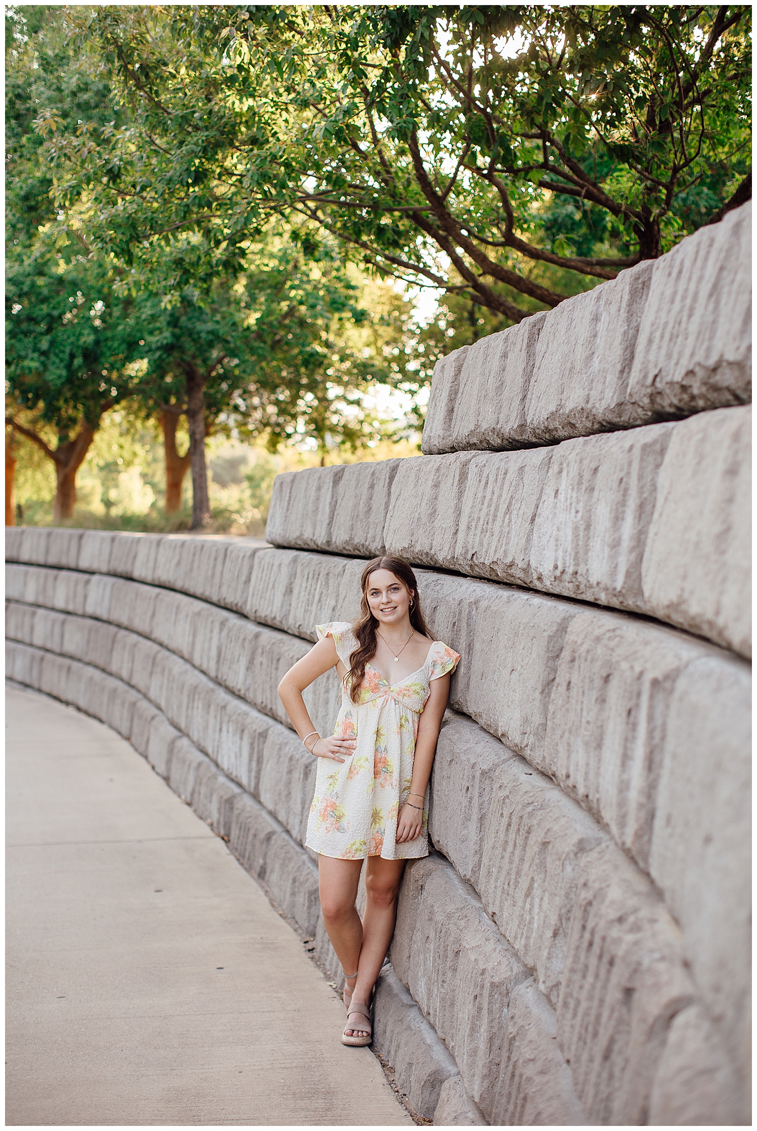 girl in yellow floral dress leaning against gray wall at Sabine Park
