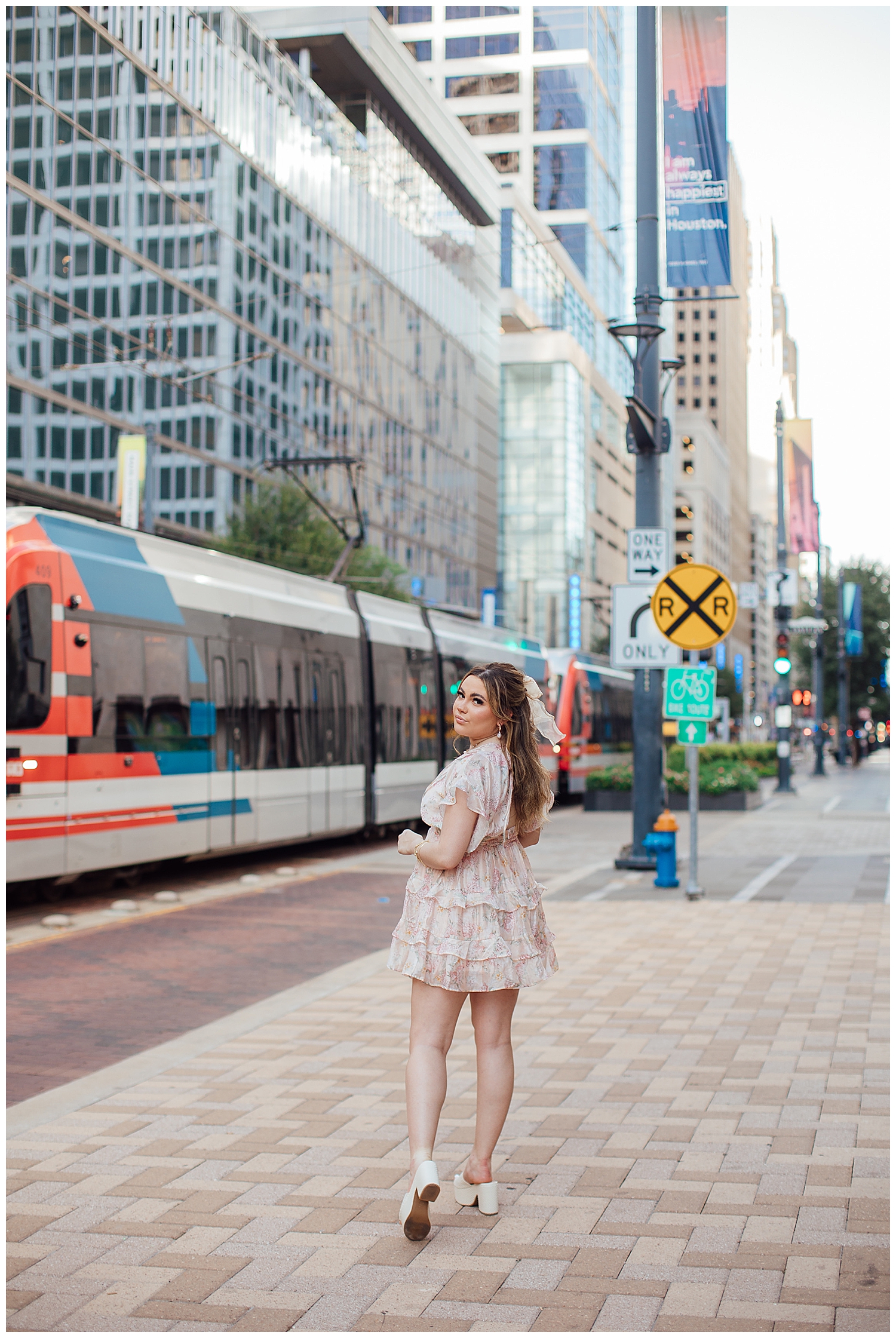 senior girl standing on Main Street Square in floral dress with METRORAIL in background