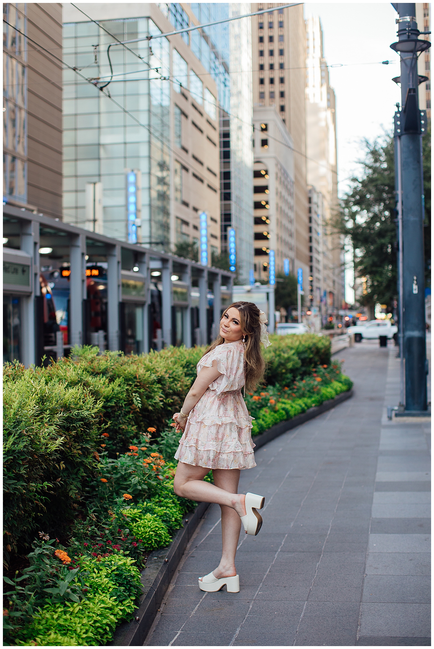 girl in floral dress kicking heel up standing on downtown Houston Main street