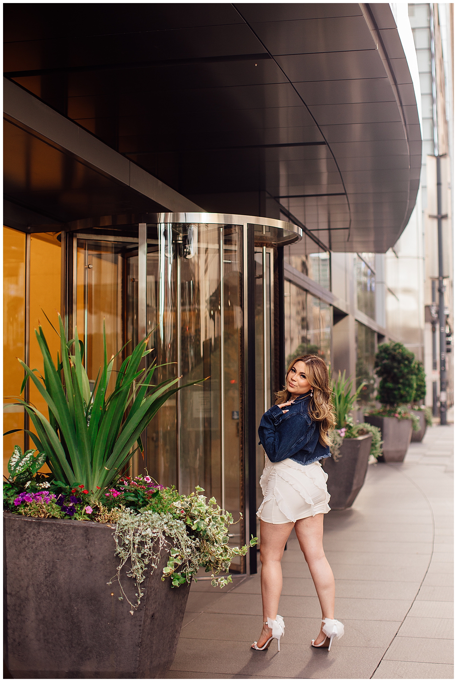 Houston downtown senior session with girl in white dress and denim jacket in front of glass windows
