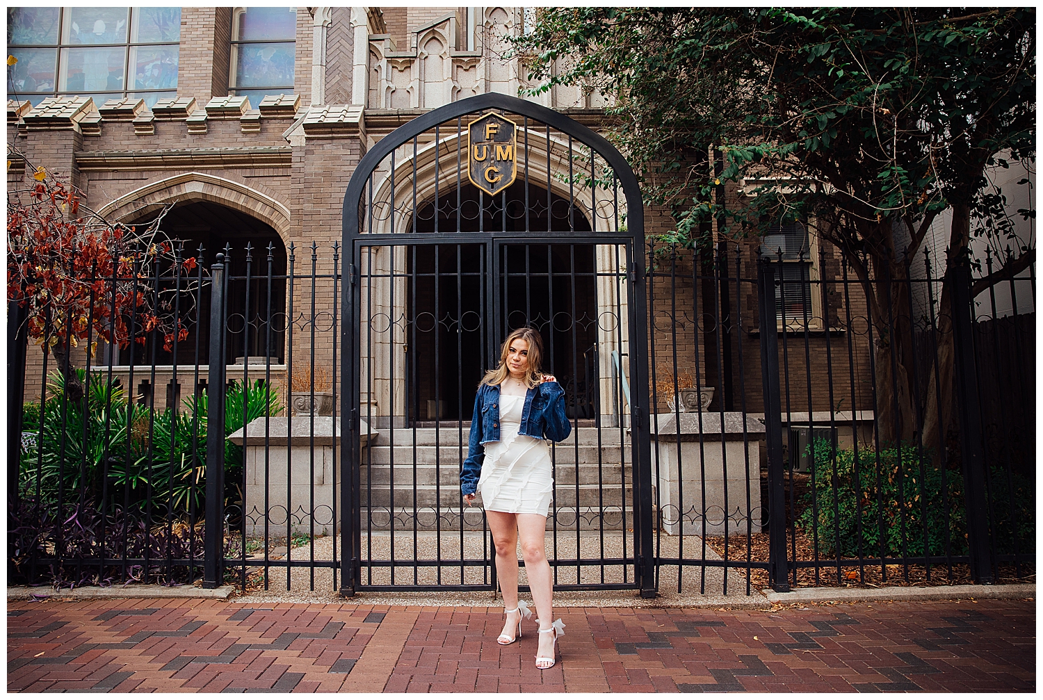 high school senior girl in dress and blue jean jacket standing in front of church gates downtown Houston