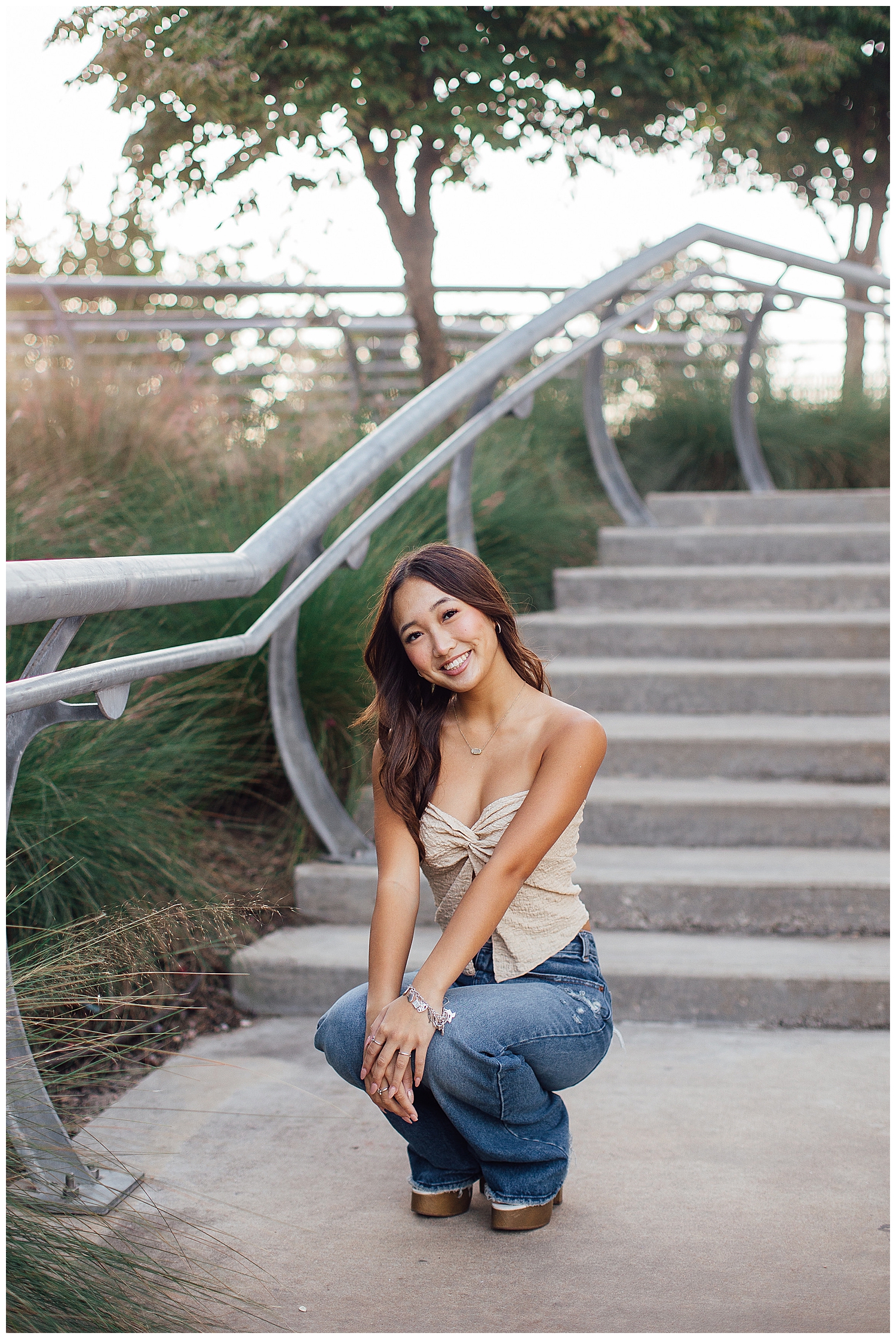 Fun senior pictures Houston downtown with girl squatting in jeans on a staircase outdoors