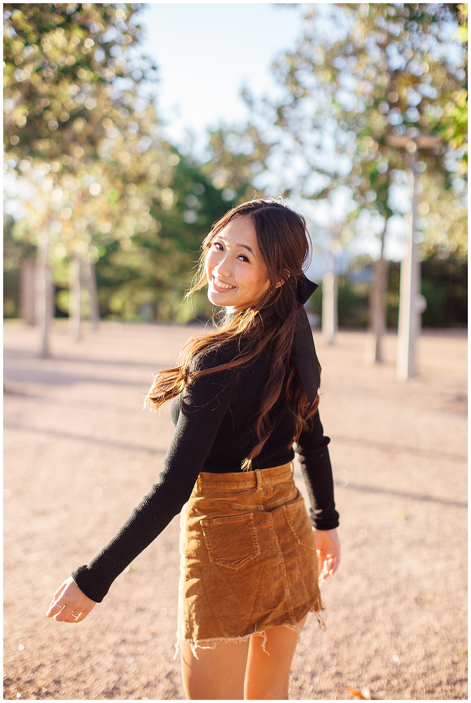 high school senior girl in black sweater and brown skirt walking Sabine Park Houston