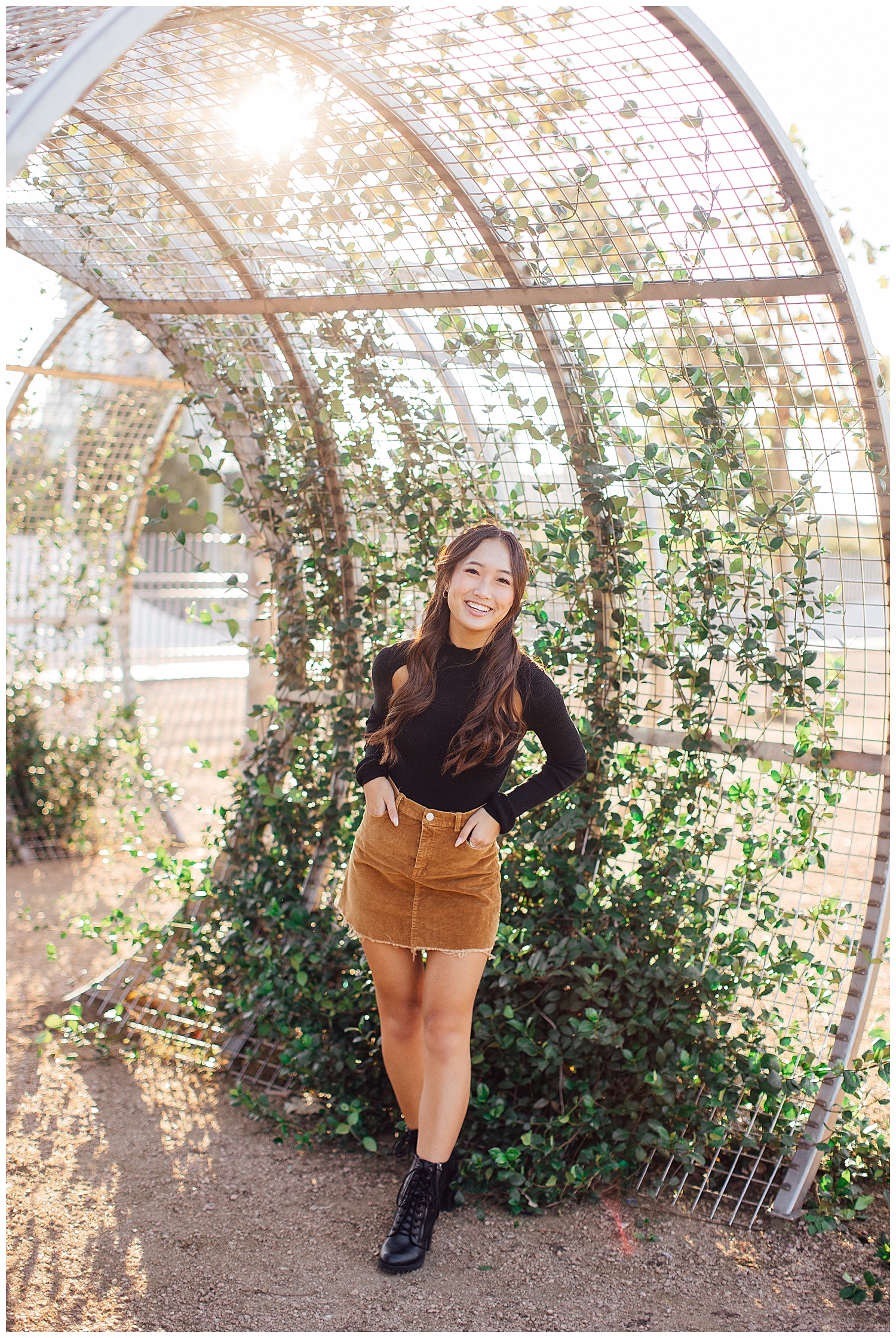 girl in black shirt and brown skirt standing in front of ivy arch for fun senior pictures Houston downtown
