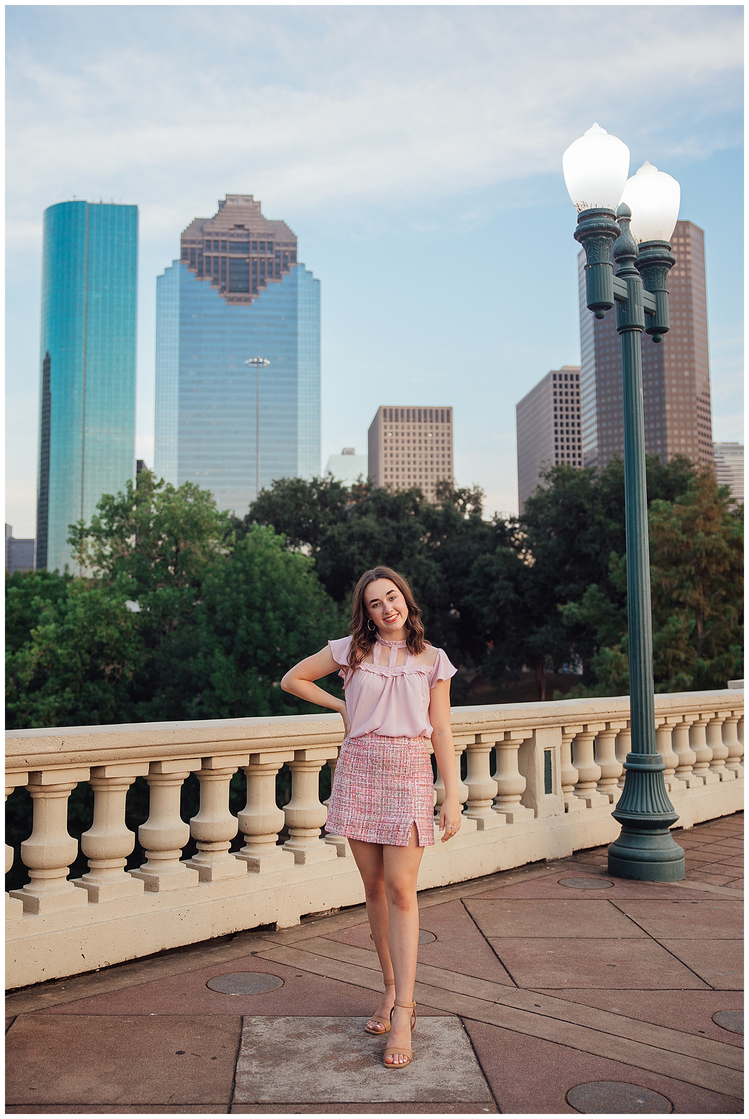 high school senior girl in pink skirt and dress standing on Sabine Bridge Houston Skyline Senior Photos