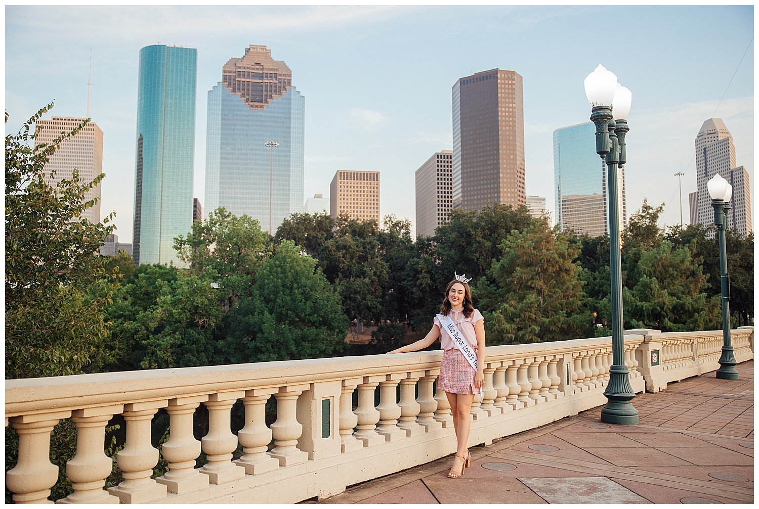 high school senior in pink dress and skirt wearing Miss Sugar Land Teen crown on Sabine Street Bridge Houston skyline