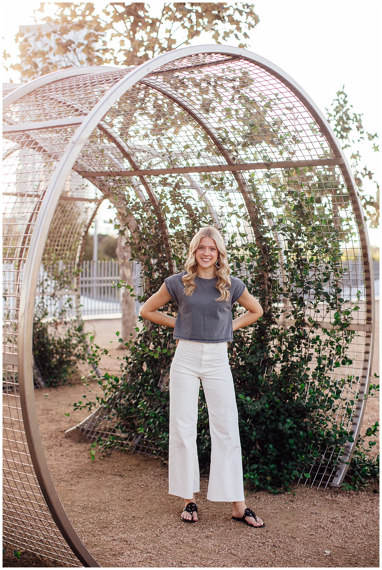 high school senior girl in white pants gray shirt standing in arch with ivy for fun senior photos Houston downtown