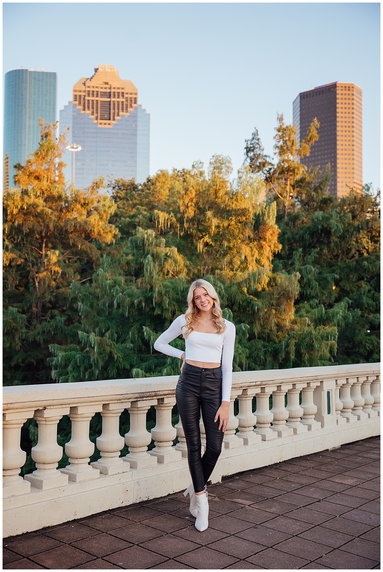 senior photos Houston Sabine Street bridge high school girl black leather pants, white shirt, white boots in front of skyline