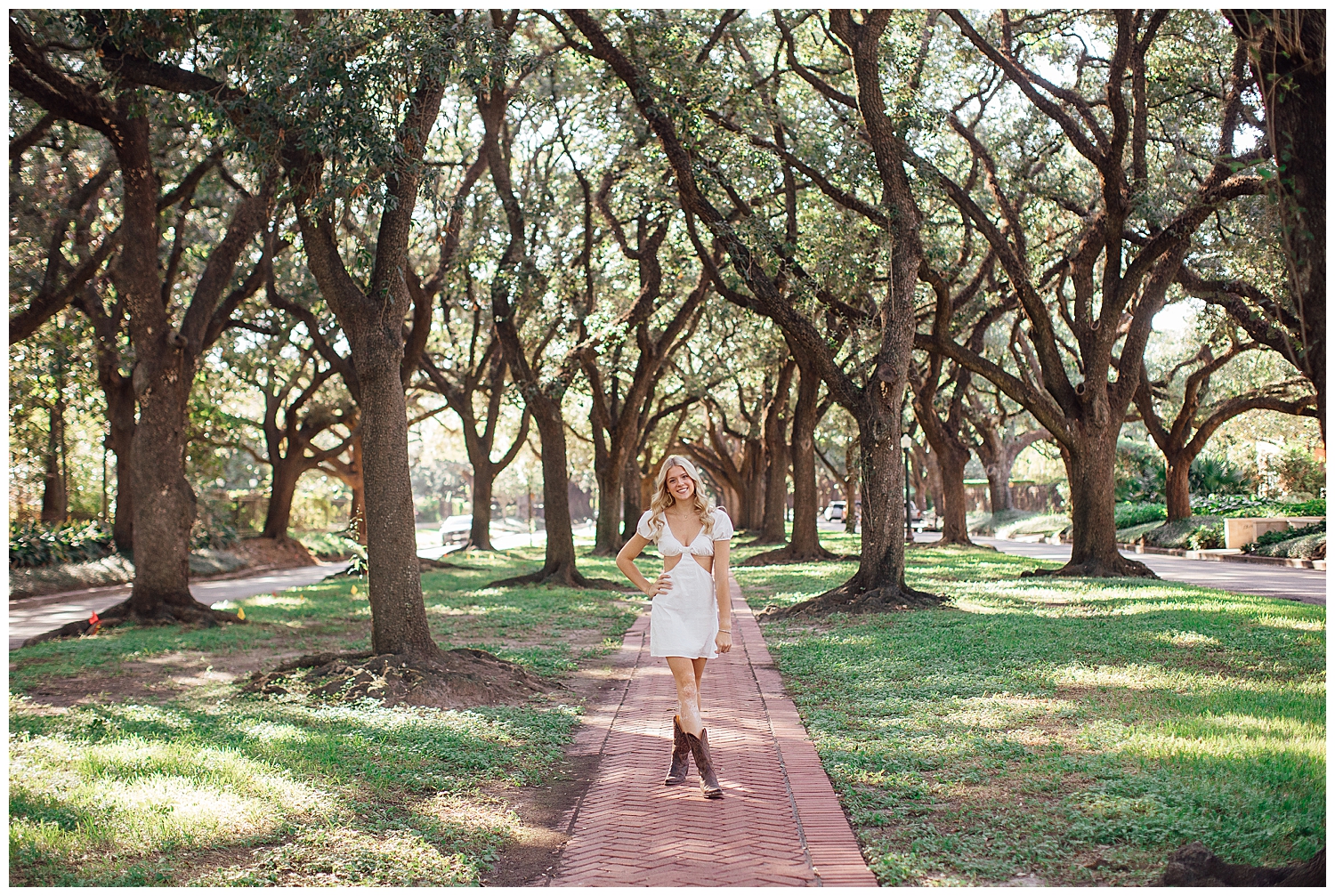 high school senior girl in white dress cowboy boots standing on sidewalk senior photos Houston treeline